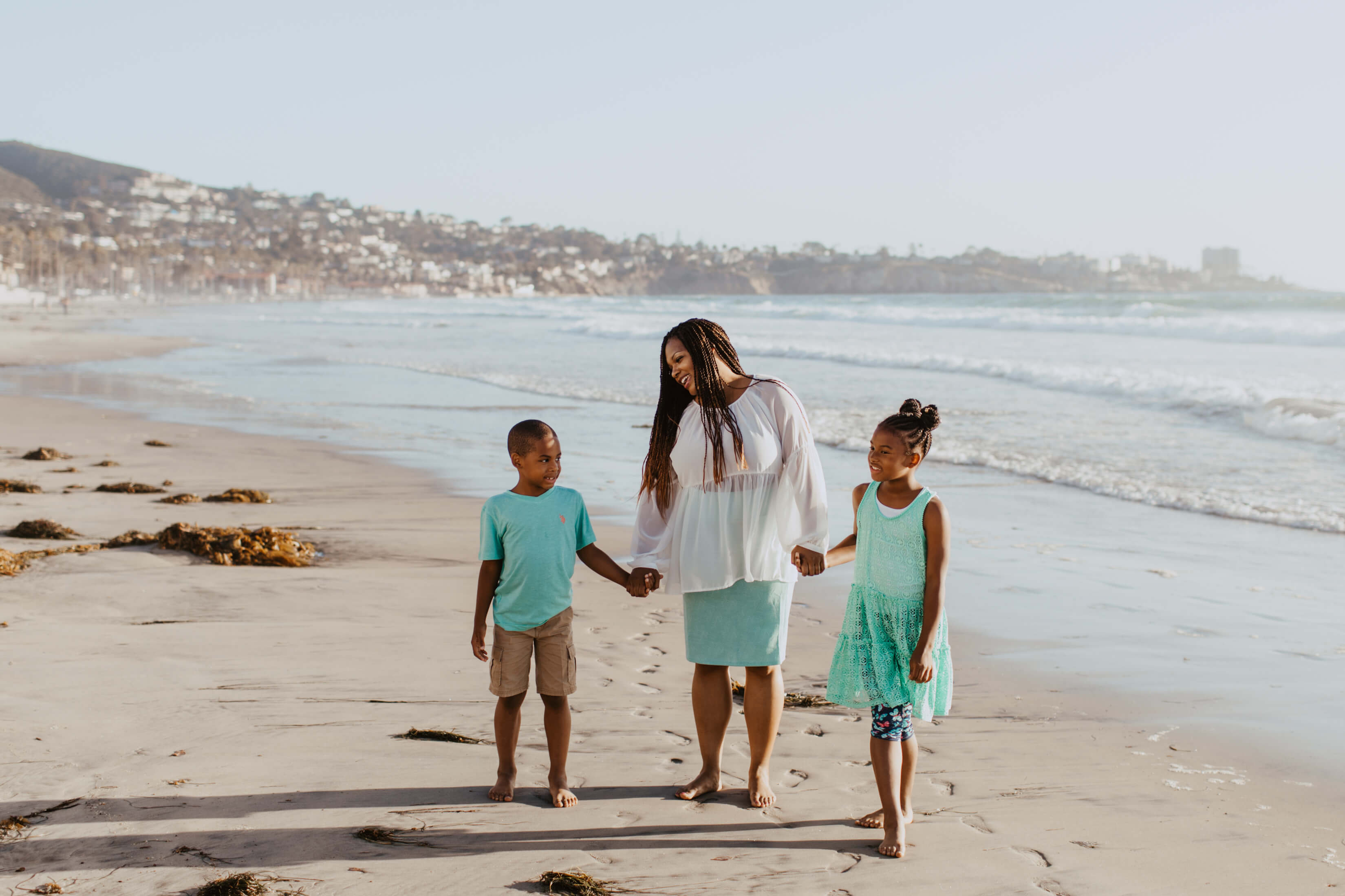 mother with son and daughter holding hands on the beach in San Diego, California