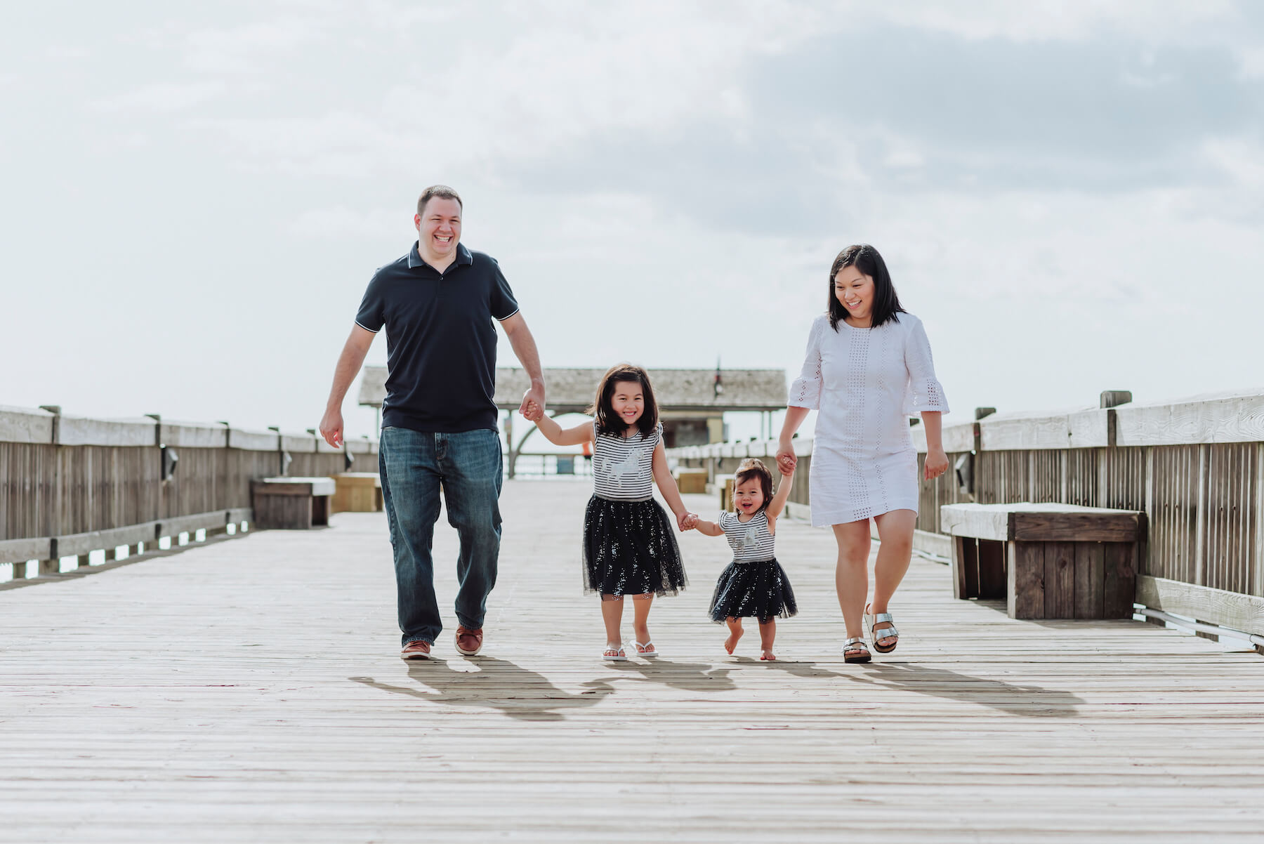 a family of four holding hands on a beach pier in Savannah, Georgia, United States of America