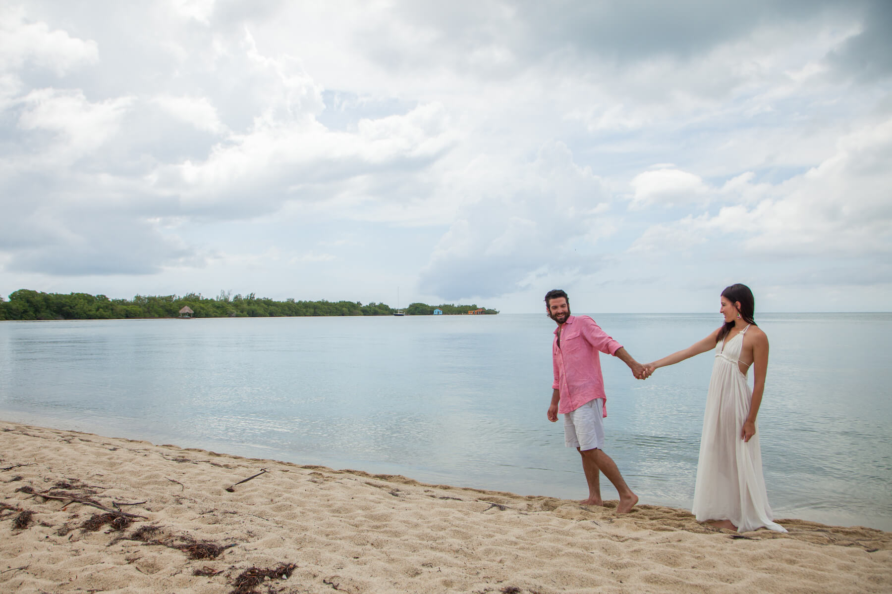 couple holding hands and walking down the beach together in Placencia, Belize