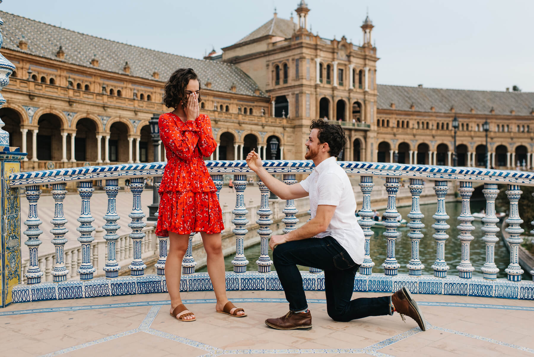 the man is proposing to the woman, he is on one knee and she is surprised at the proposal in Seville, Spain