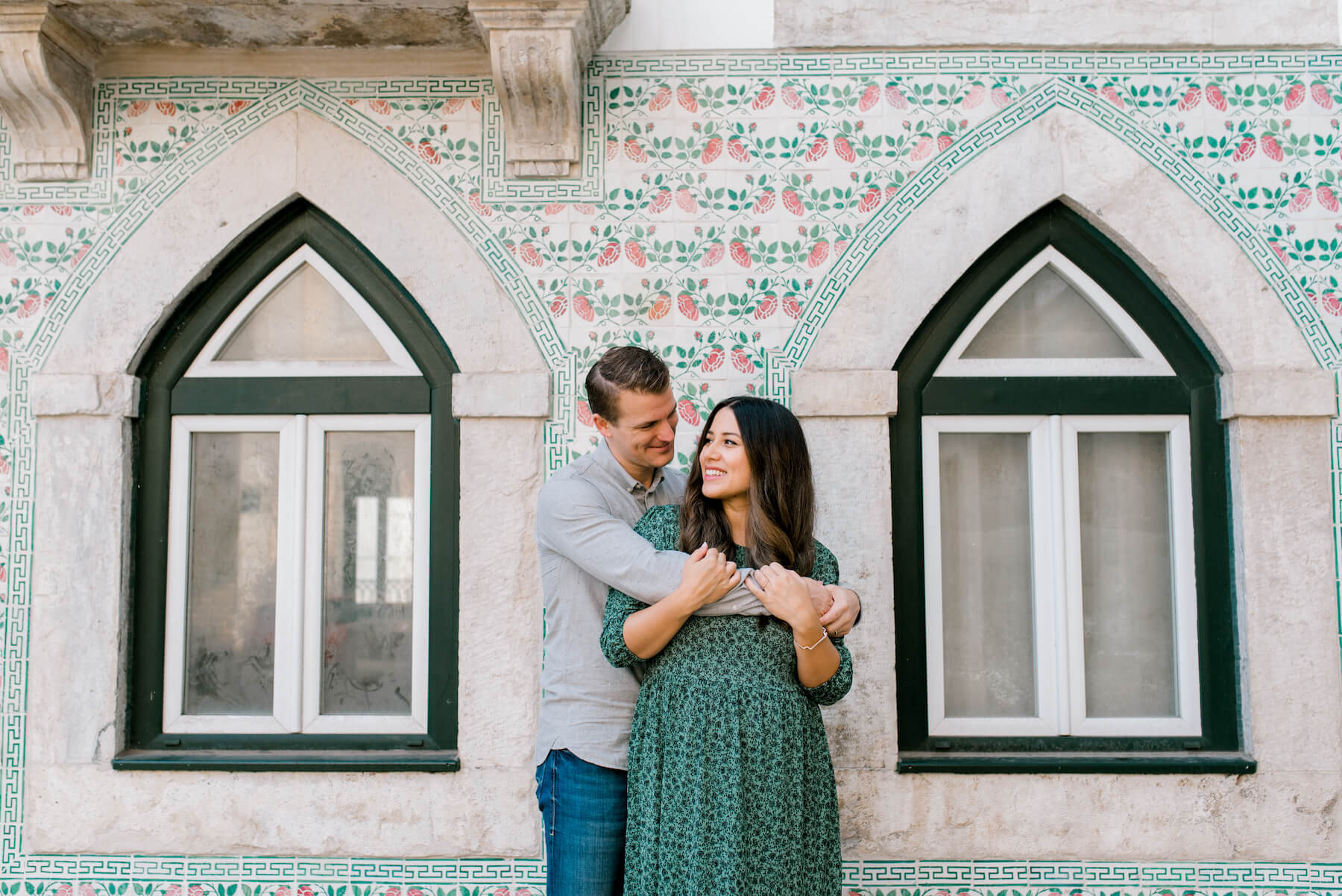 couple hugging each other and standing in front of a colorful building in Lisbon, Portugal