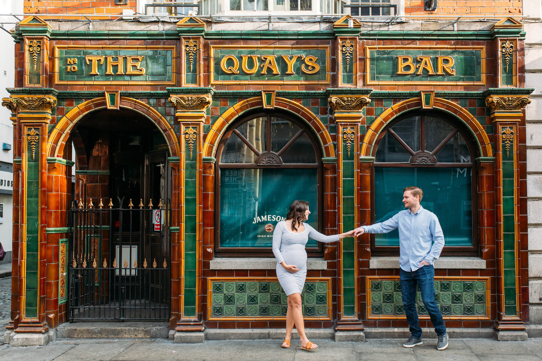 a pregnant couple standing in front of a pub in Dublin, Ireland