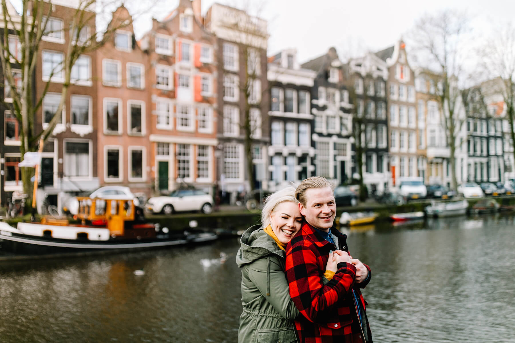 couple holding each other with beautiful row houses in the background in Amsterdam, Netherlands