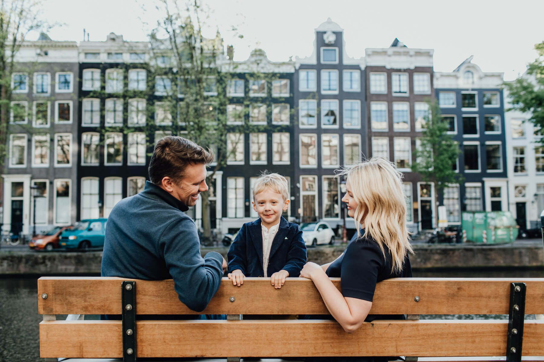 family sitting on a bench near the canal in Amsterdam, Netherlands