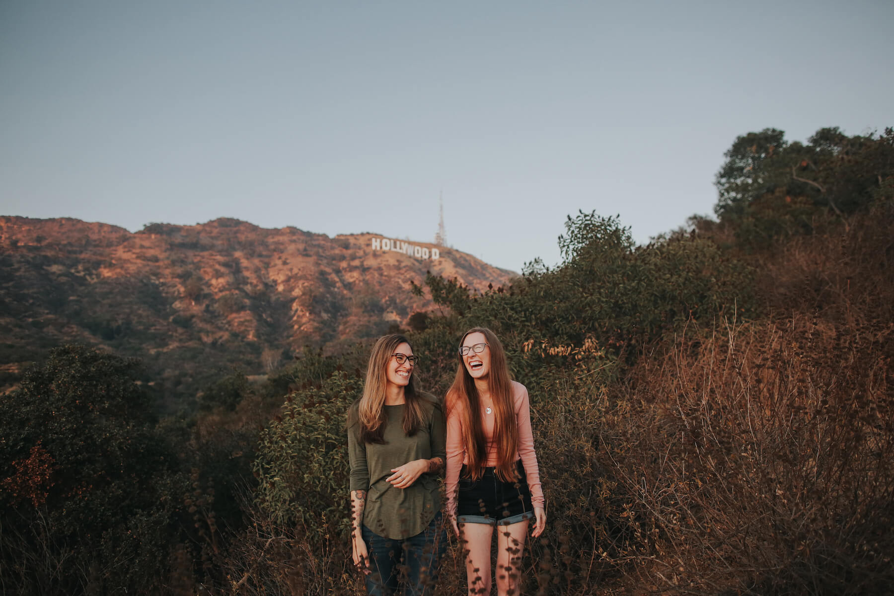 two girls standing and laughing with the Hollywood sign in the background in Los Angeles, California