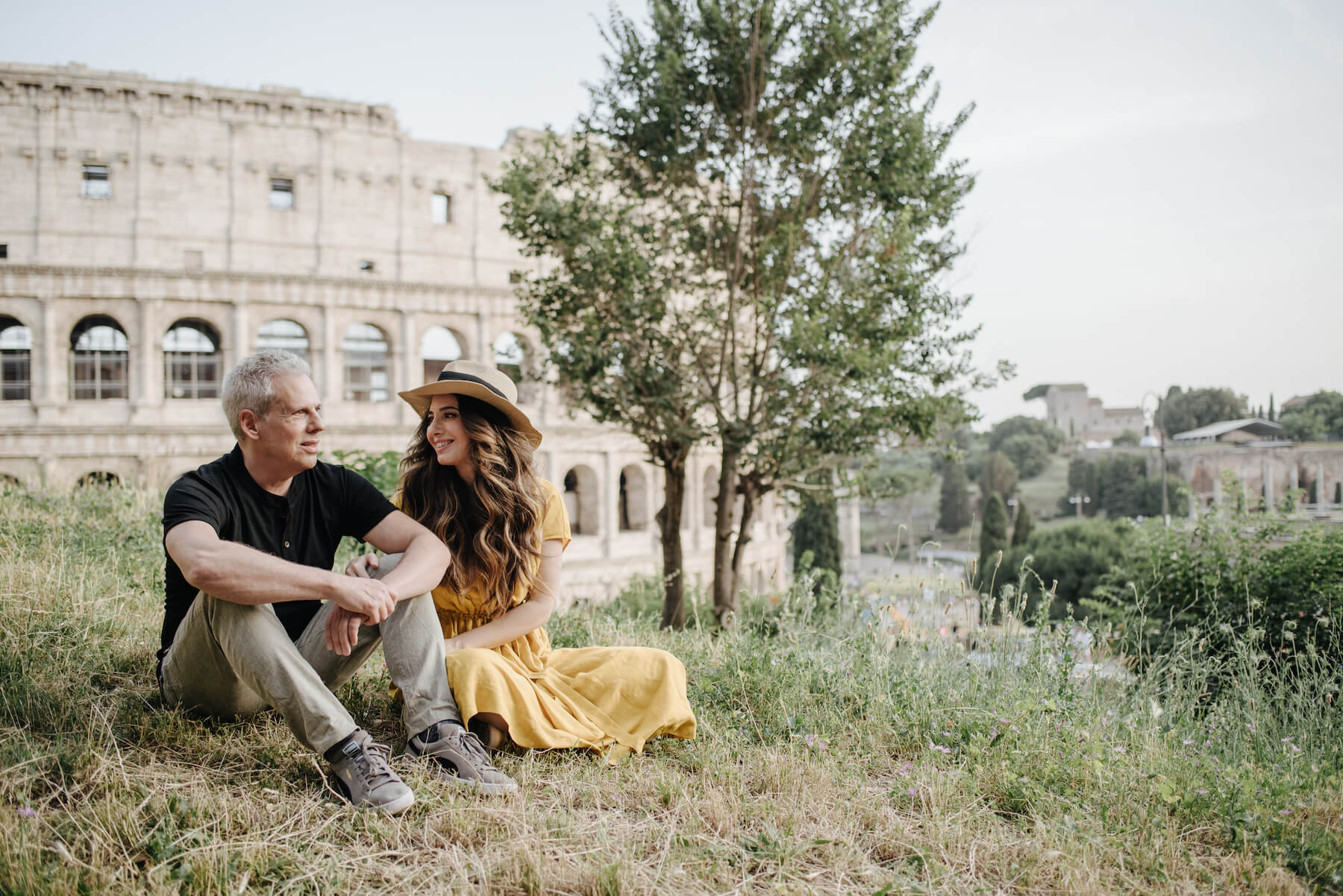 couple sitting on a hill in front of the colosseum in Rome, Italy