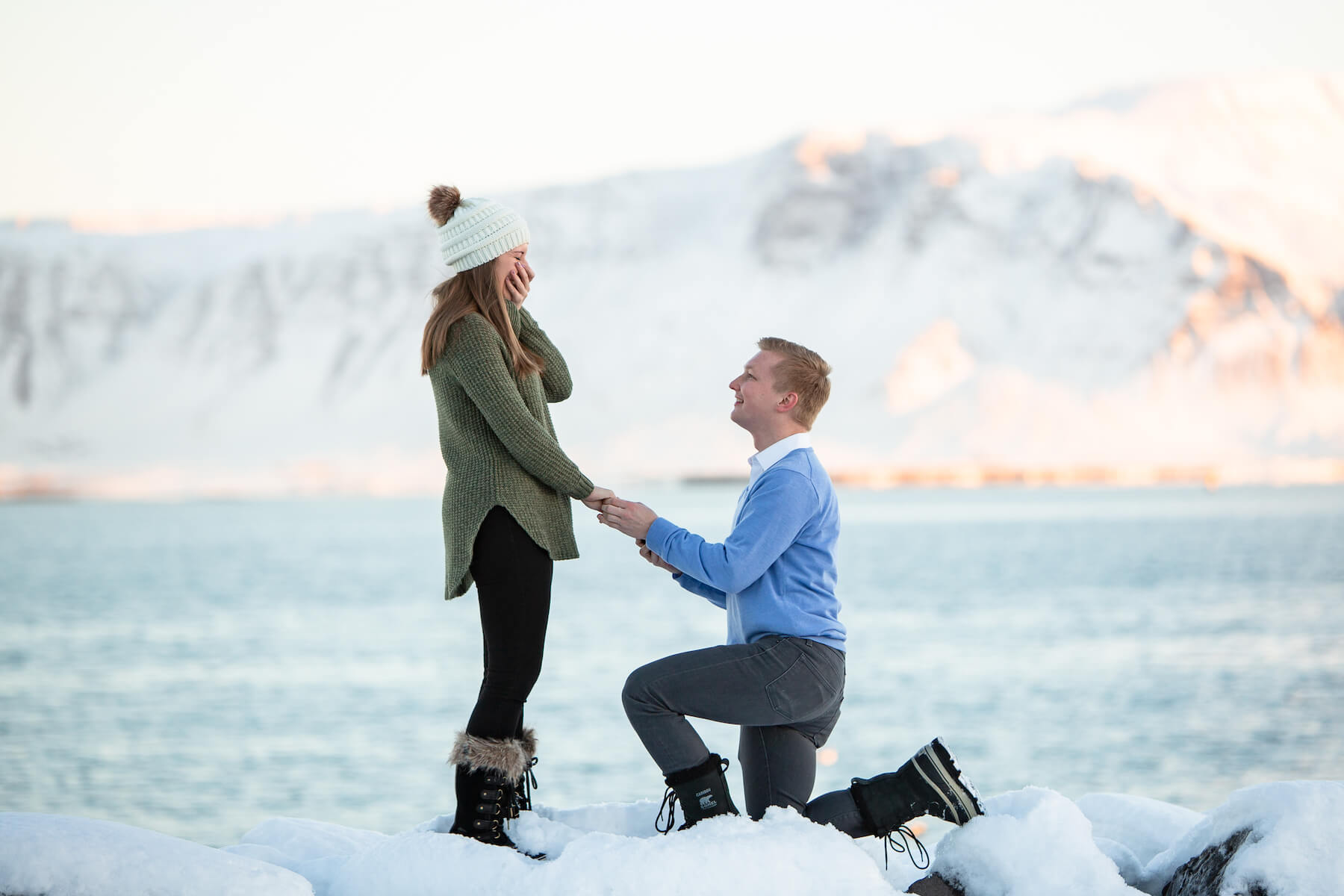 a man is proposing to the woman, standing in the snow in Reykjavik, Iceland