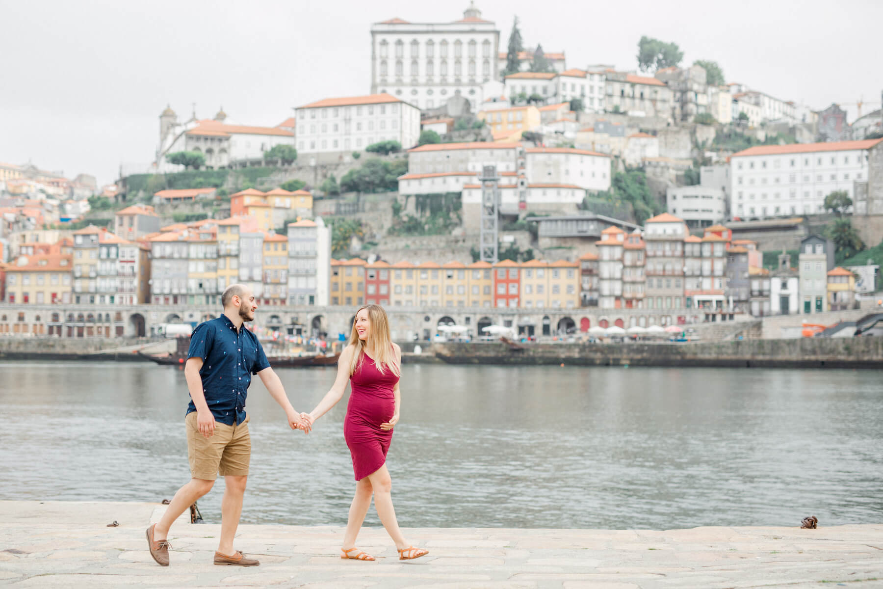 pregnant couple holding hands and walking in Porto, Portugal