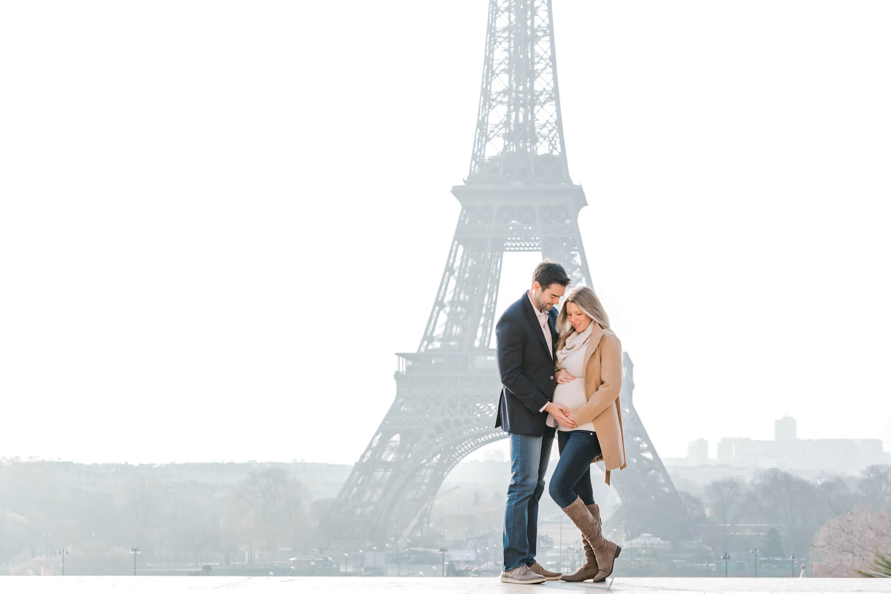 pregnant couple in looking at the woman's belly in front of the Eiffel Tower in Paris, France