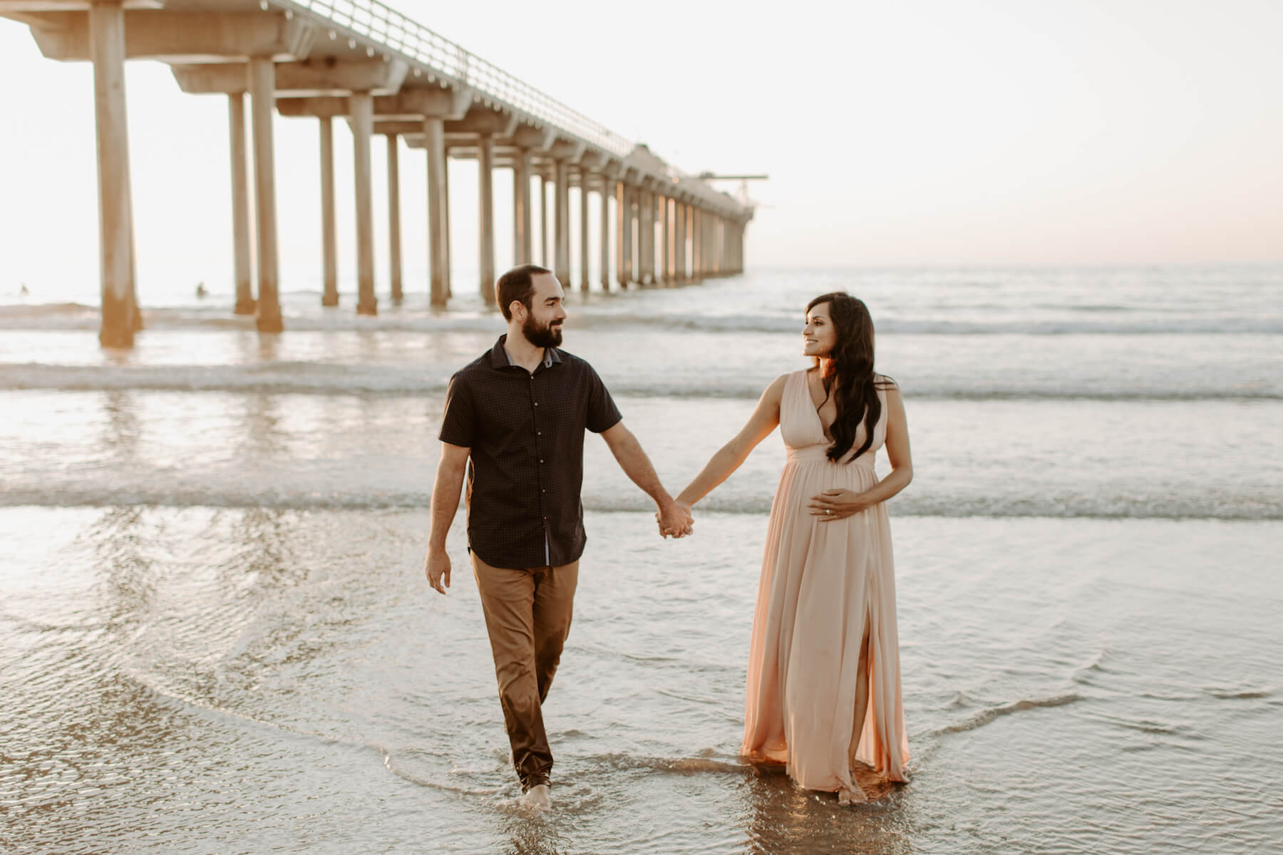 pregnant couple standing on the beach near the ocean in San Diego, California