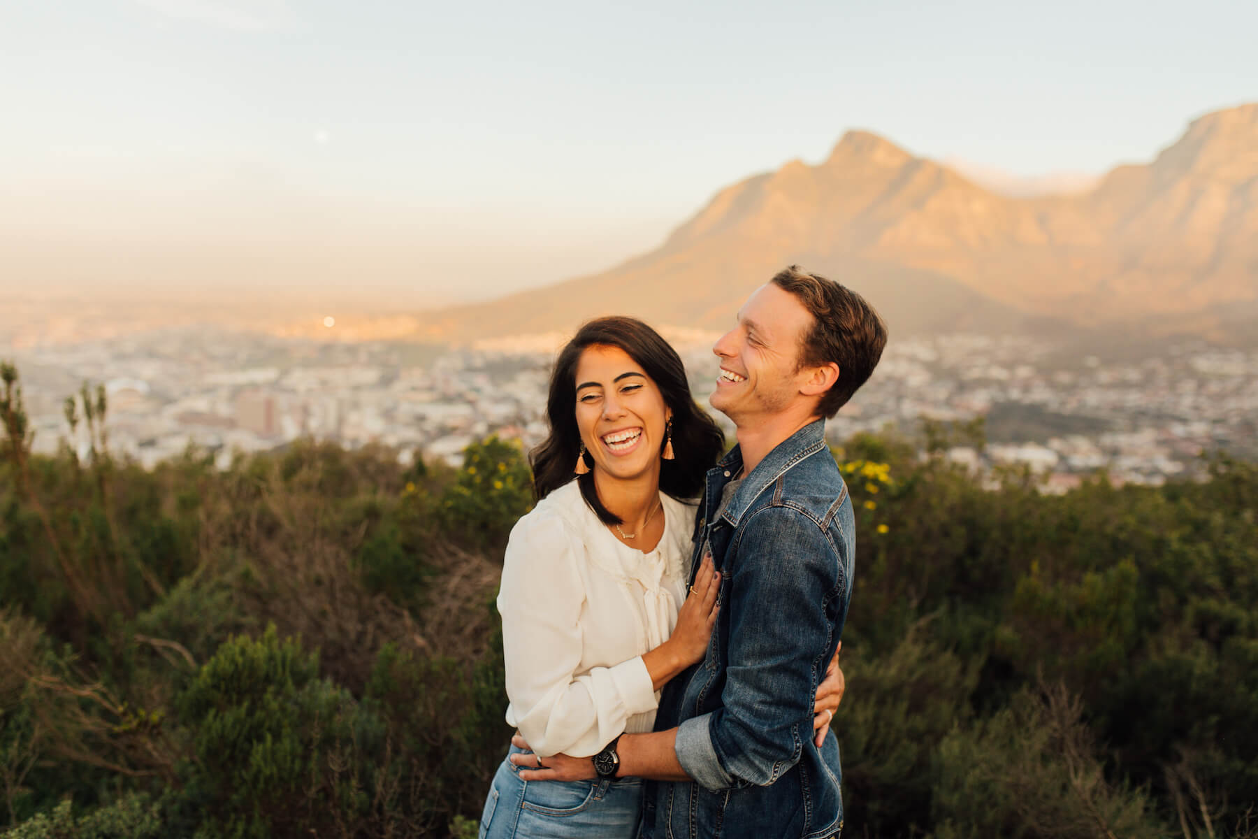 couple holding each other and laughing on a hill in Cape Town, South Africa