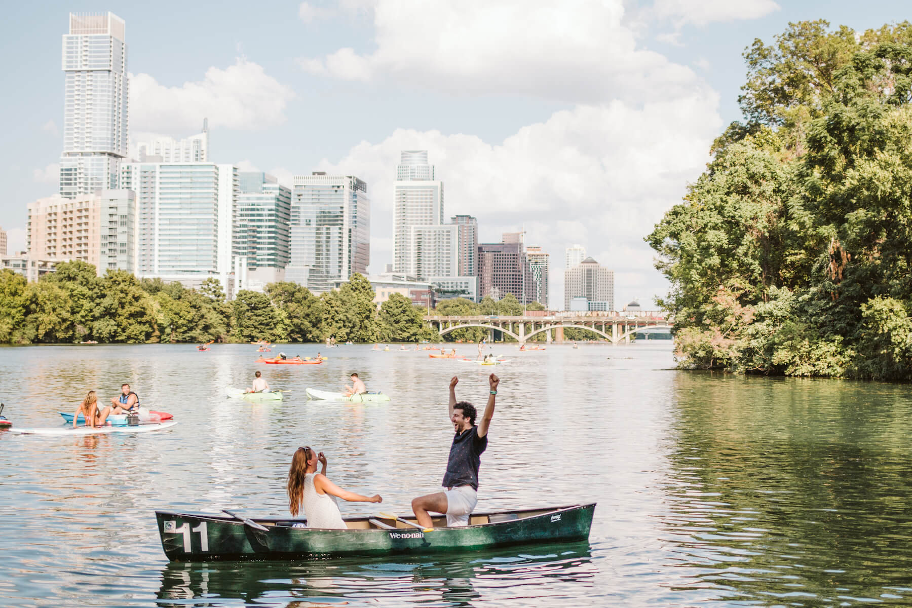 couple in a row boat, the man has his hands in the air, he just proposed to the woman in Austin, Texas