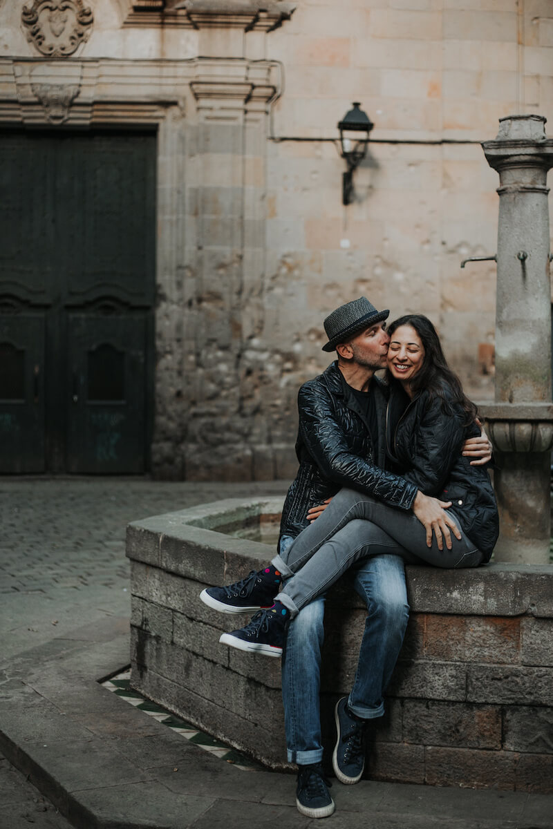 couple sitting down on the ledge of a fountain in Barcelona, Spain