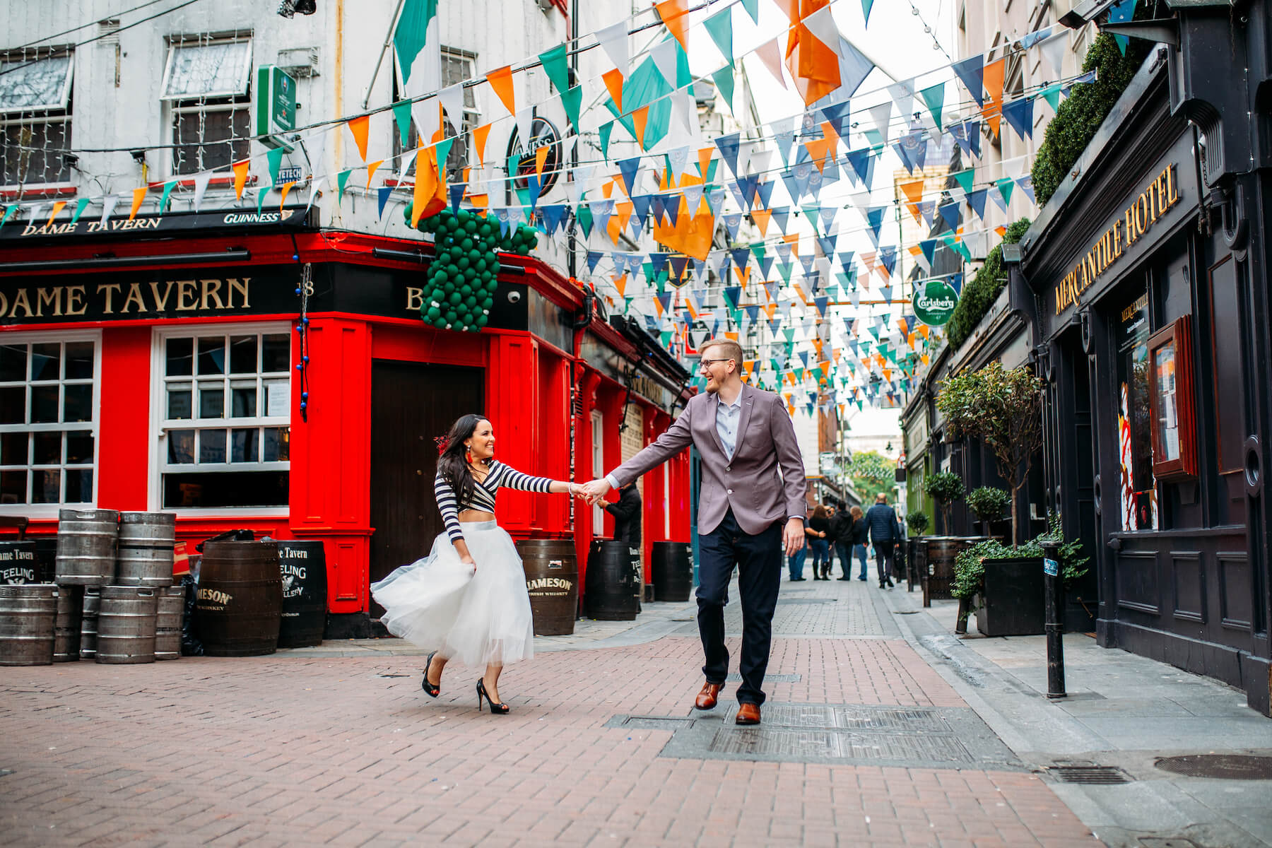 couple holding hands and dancing in front of a pub in Dublin, Ireland