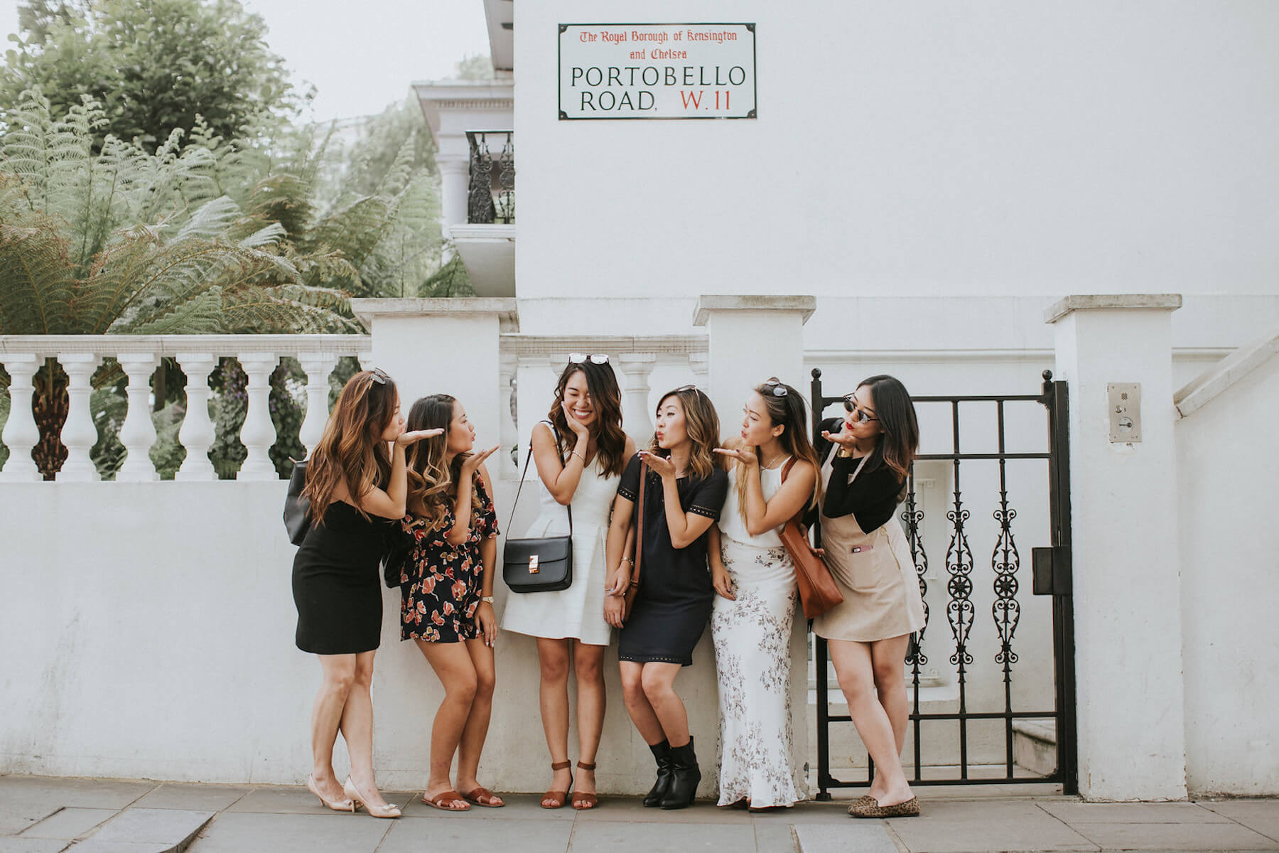 girlfriends handing out under the Portobello market sign in London, England