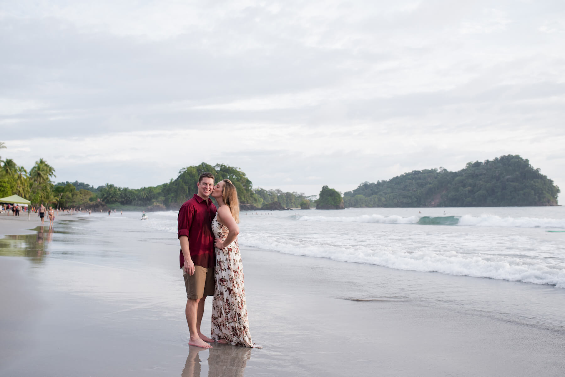 couple standing on the beach and the woman is kissing the man in Manuel Antonio, Costa Rica
