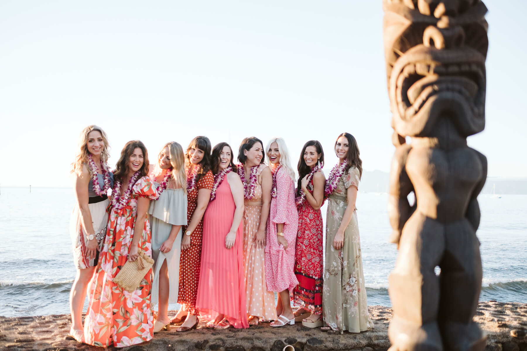 9 girlfriends on a girls trip are standing on the beach wearing colorful dresses and having fun in Maui, Hawaii