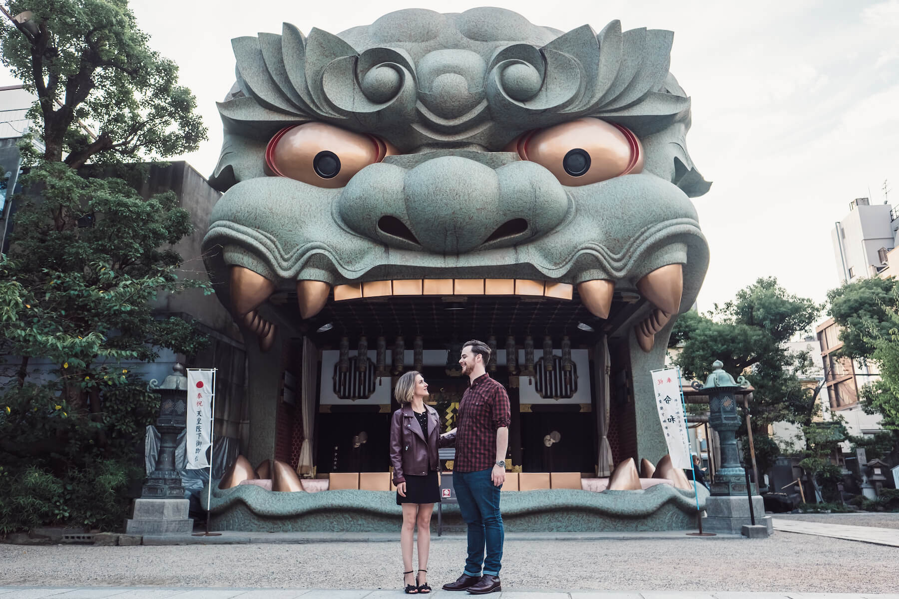 couple looking at each other in front of a statue of a dragon in Osaka, Japan