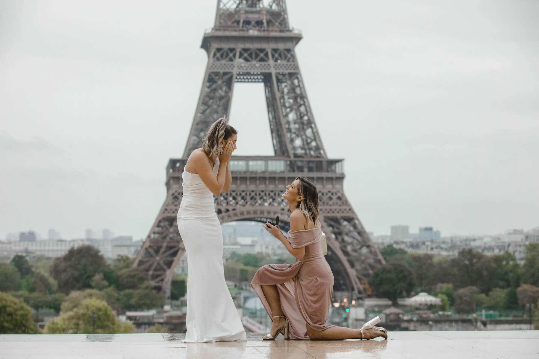 LGBTQ couple in front of the Eiffel tower and one of the women is proposing to the other woman.