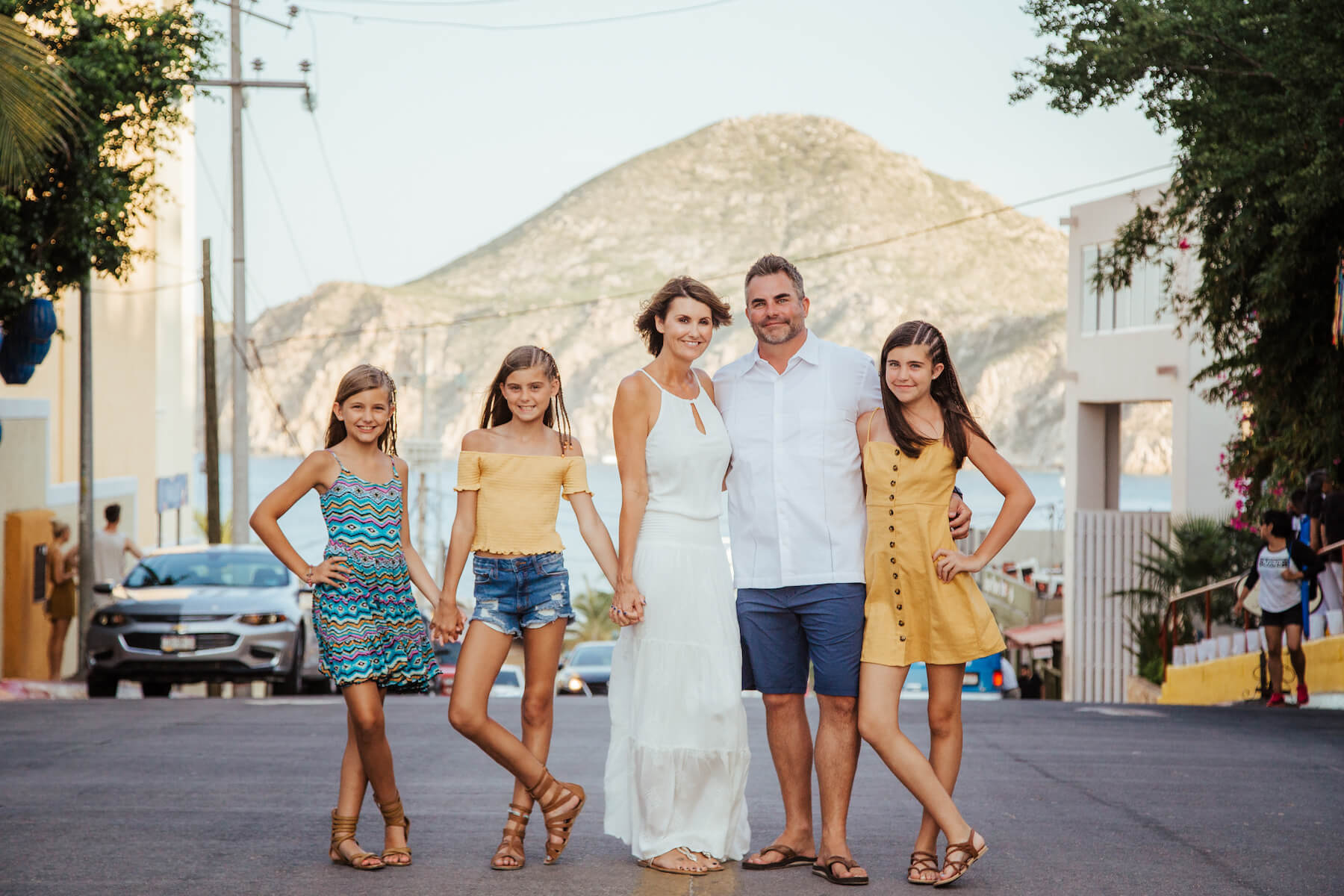 family of five standing in the middle of a street with the ocean in the background in Cabo San Lucas, Mexico