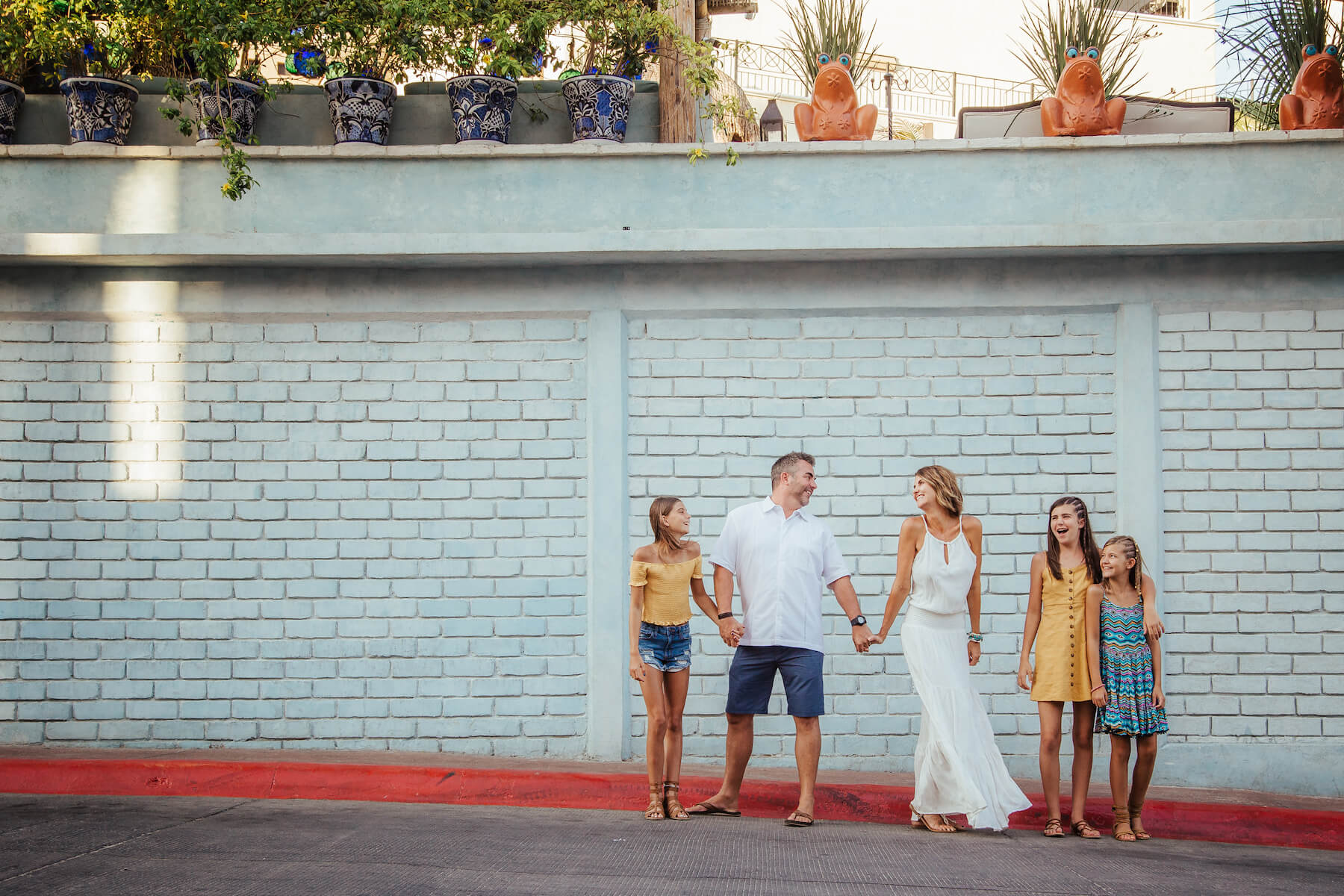 family of five standing in front of a colourful building in Cabo San lucas, Mexico