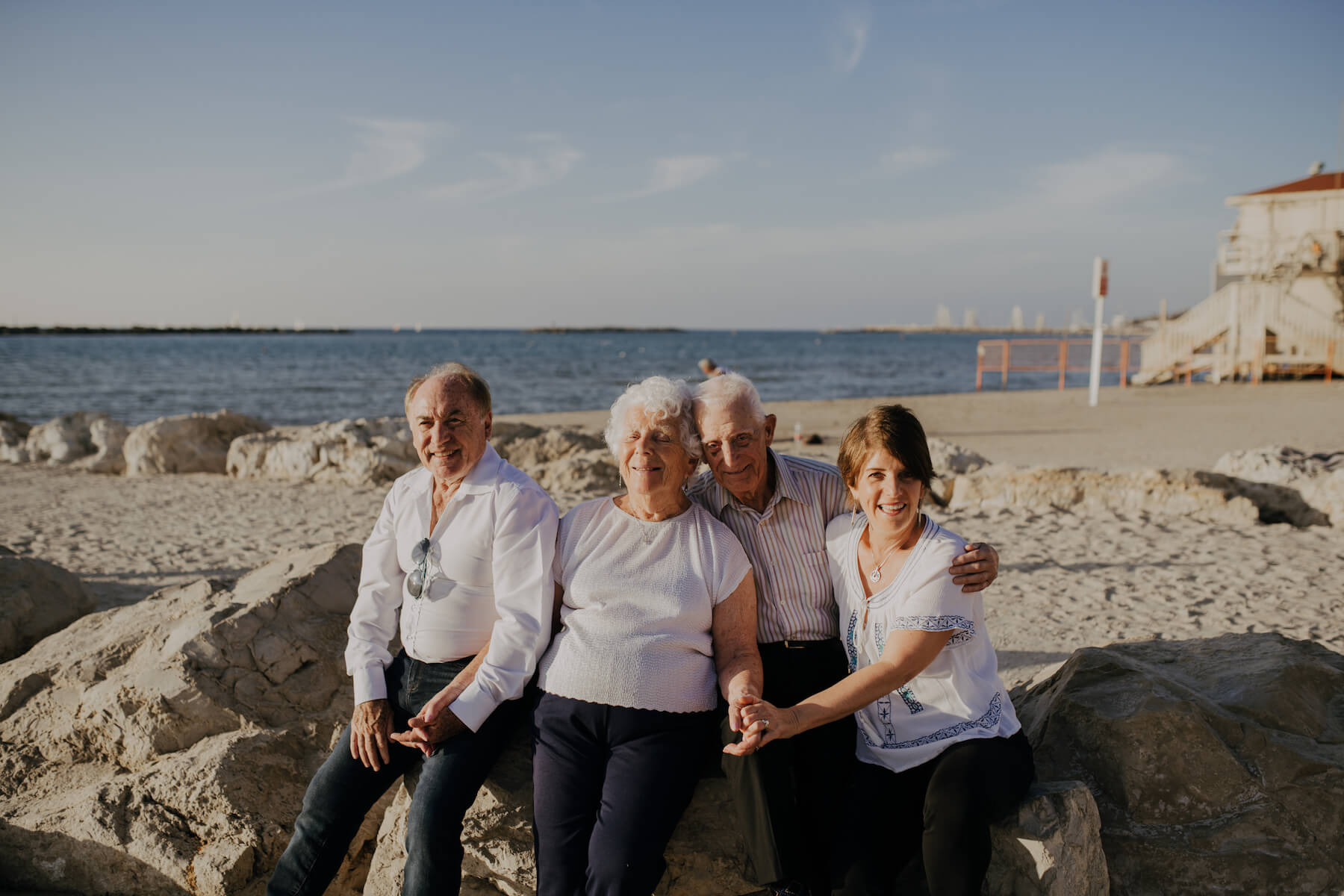 family of 4 sitting on a rock on the beach in Tel Aviv, Israel