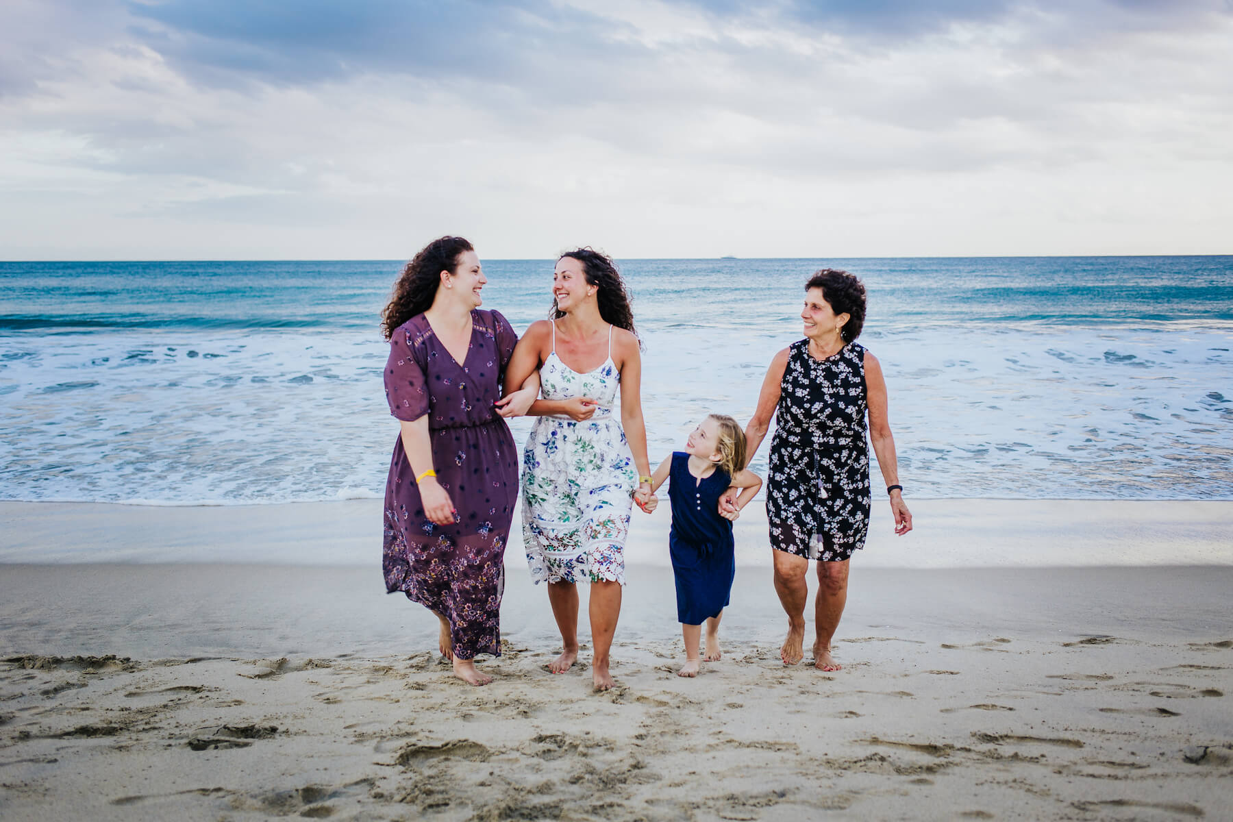 multigenerational family with a toddler holding hands and arms on the beach in Cabo San Lucas, Mexico