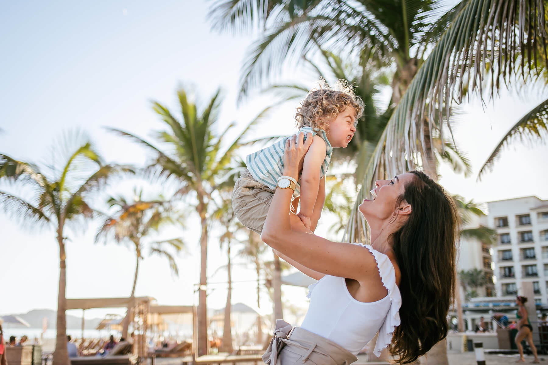 Mother holding her toddler in the air on the beach in Cabo San Lucas, Mexico