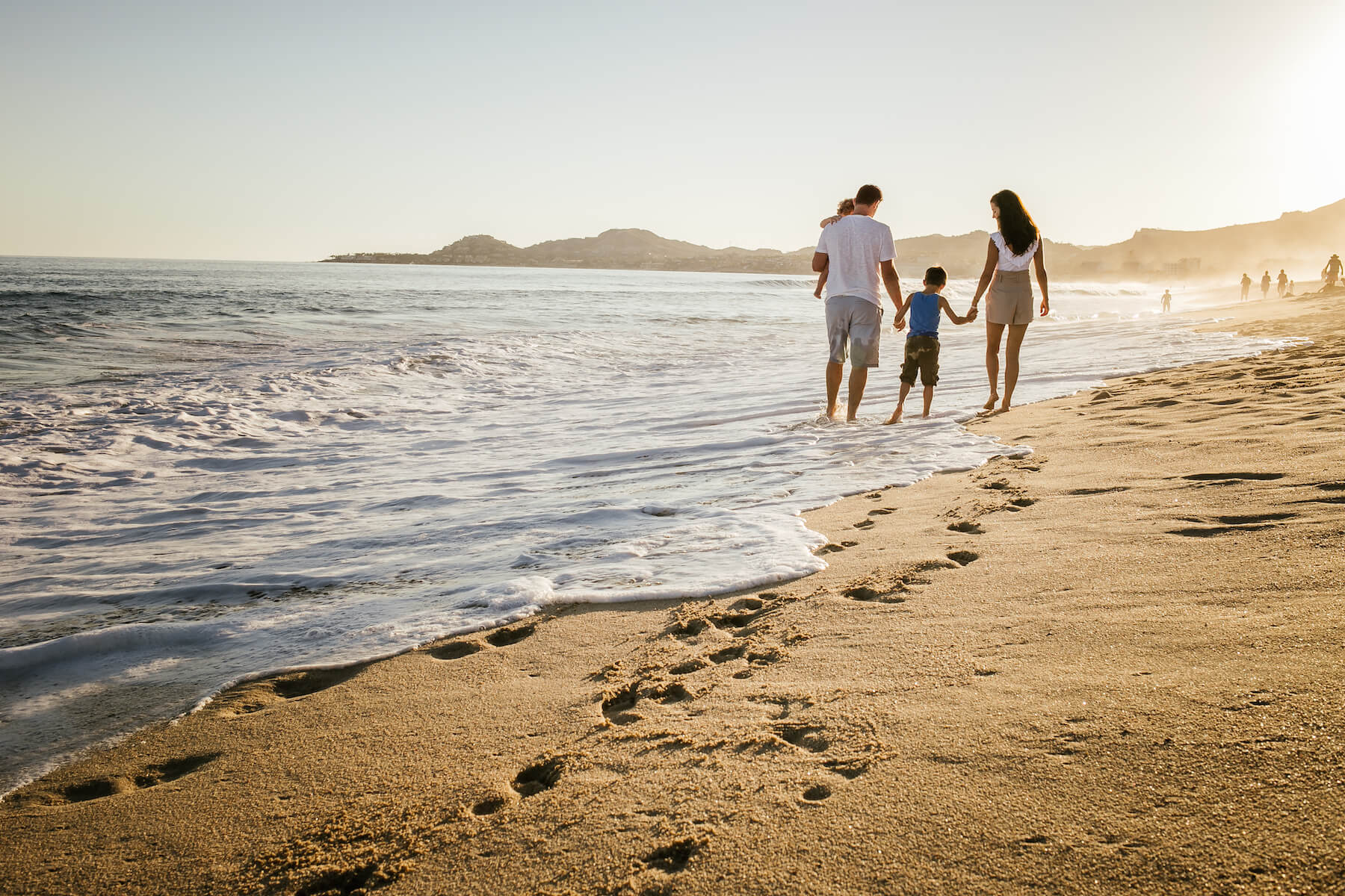 family of four holding hands and walking on the beach in Cabo San Lucas, Mexico