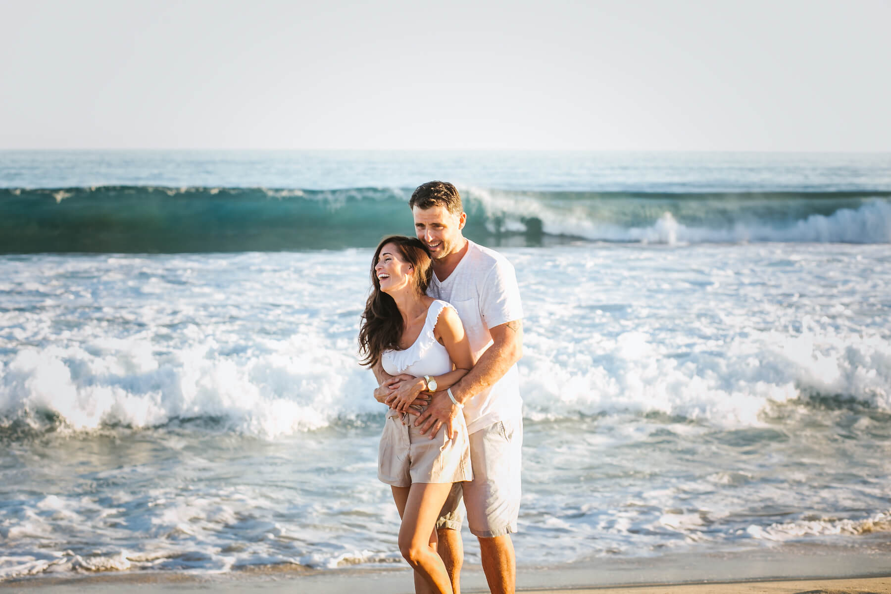 couple holding each other on the beach with the ocean in the background in Cabo San Lucas, Mexico