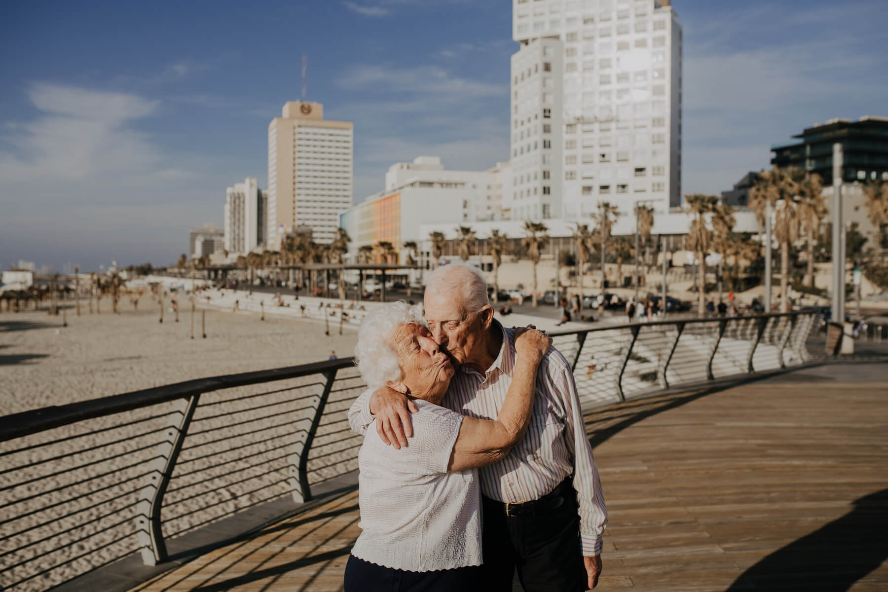 older couple giving each other a kiss on the boardwalk near the beach in Tel Aviv, Israel
