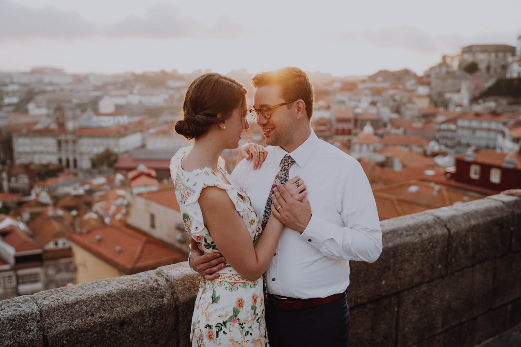 couple holding hands and hugging, with the city of Porto in the background in Porto, Portugal