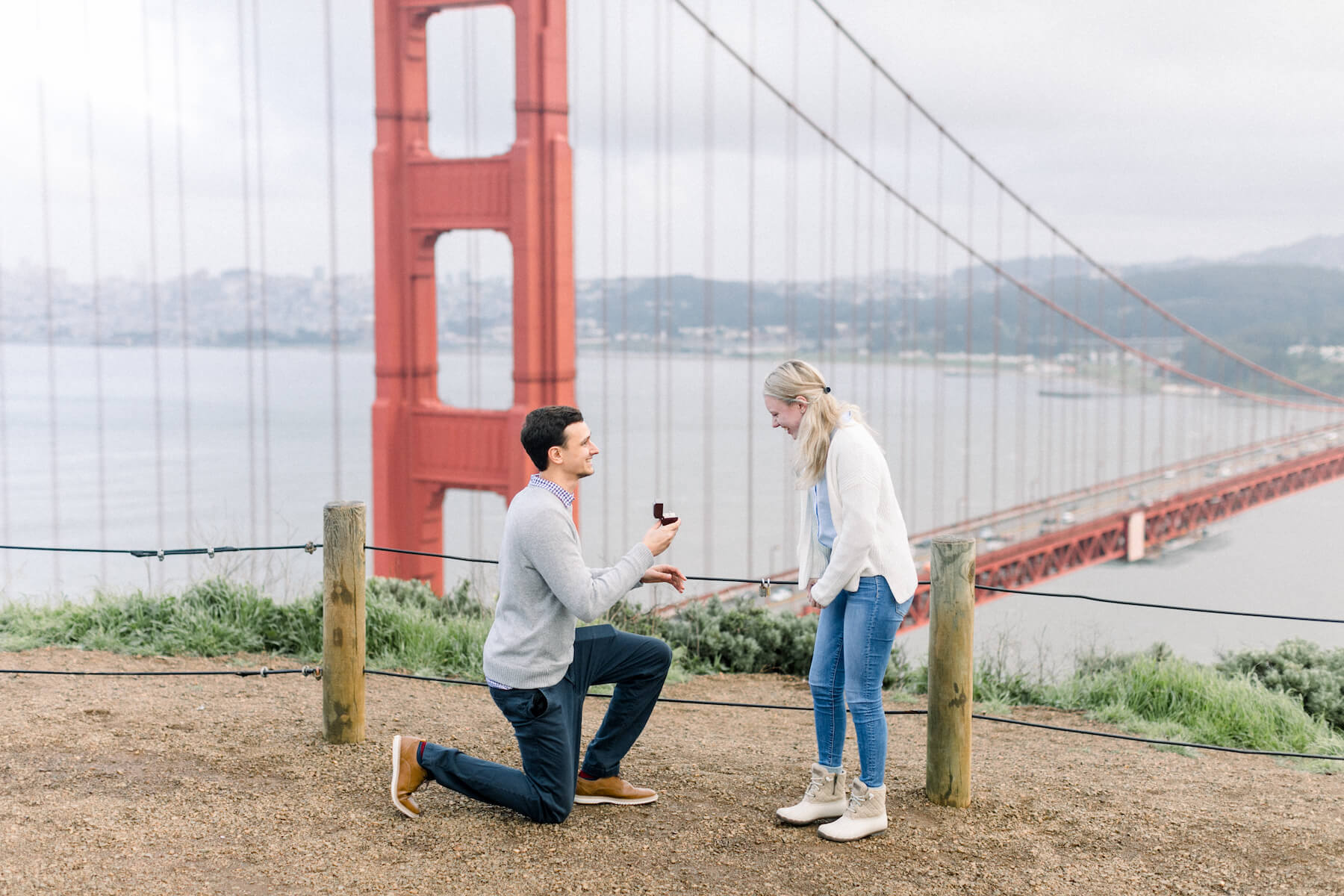 a man proposing to a woman with San Francisco bridge in the background in San Francisco, California