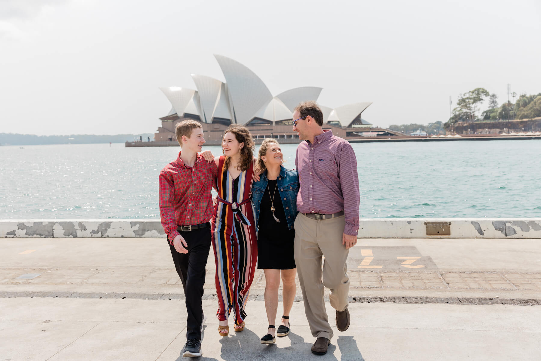 Family of 4 walking with the Sydney Opera house in Australia behind them