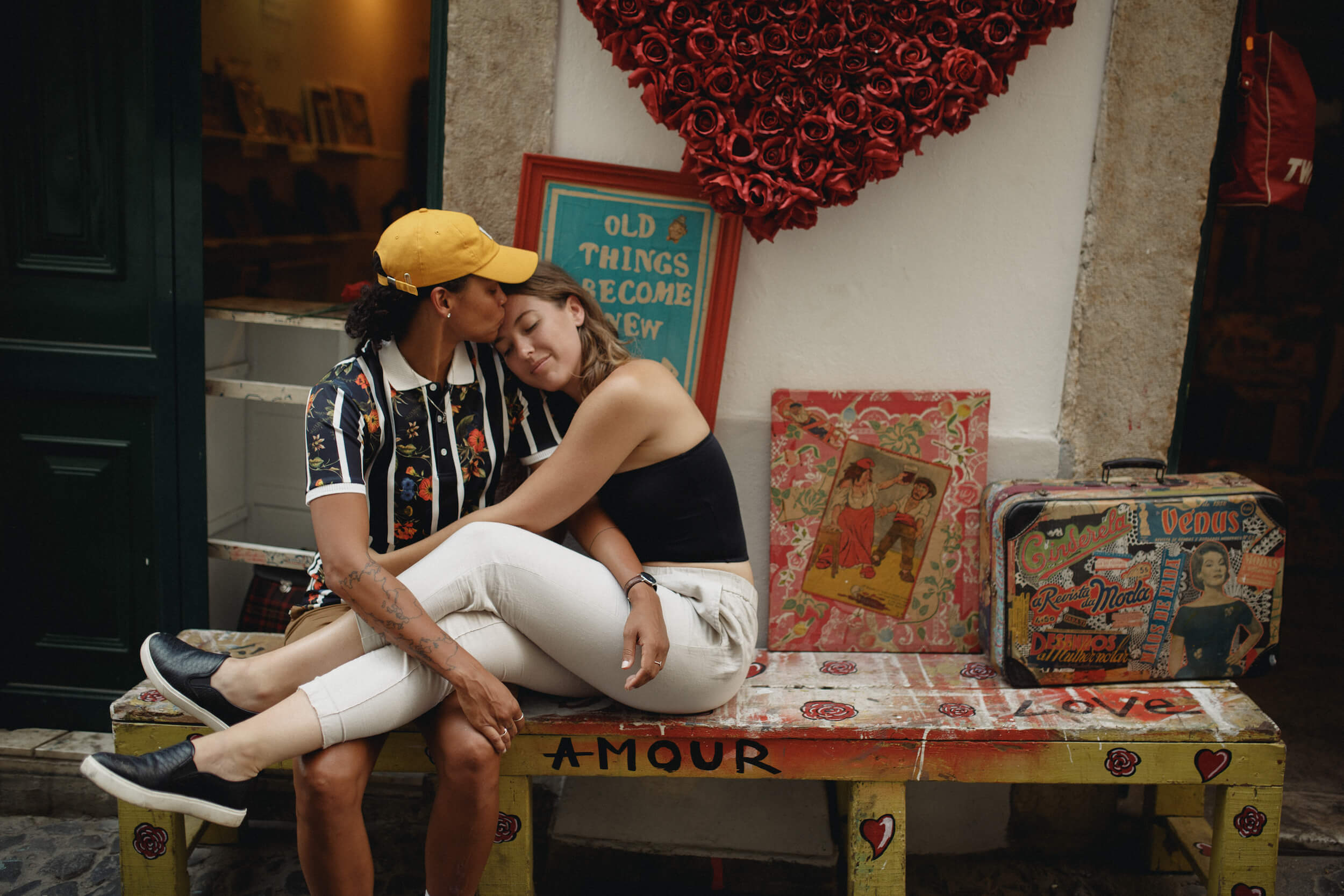 A couple snuggle and kiss on a bench in Lisbon, Portugal.