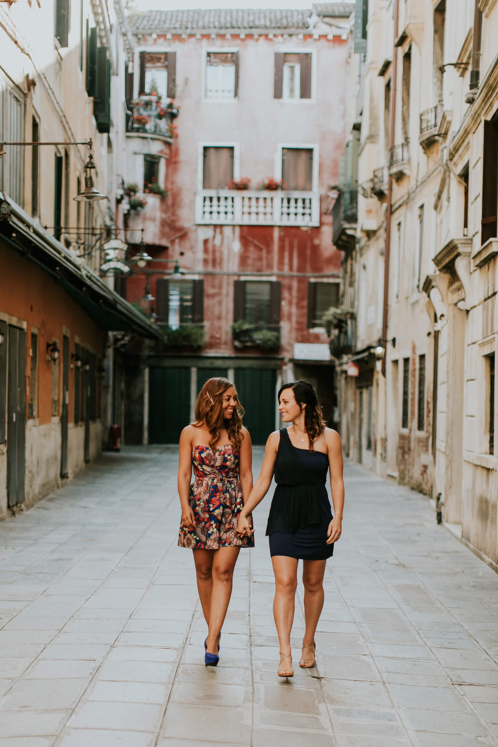 A Lesbian couple holds hands strolling the streets of Venice, Italy.