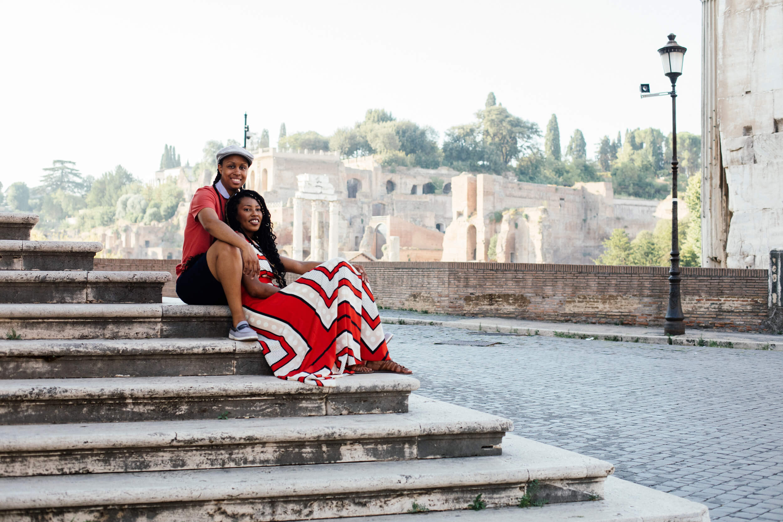 Two woman hold each other while sitting on stairs in Rome, Italy.