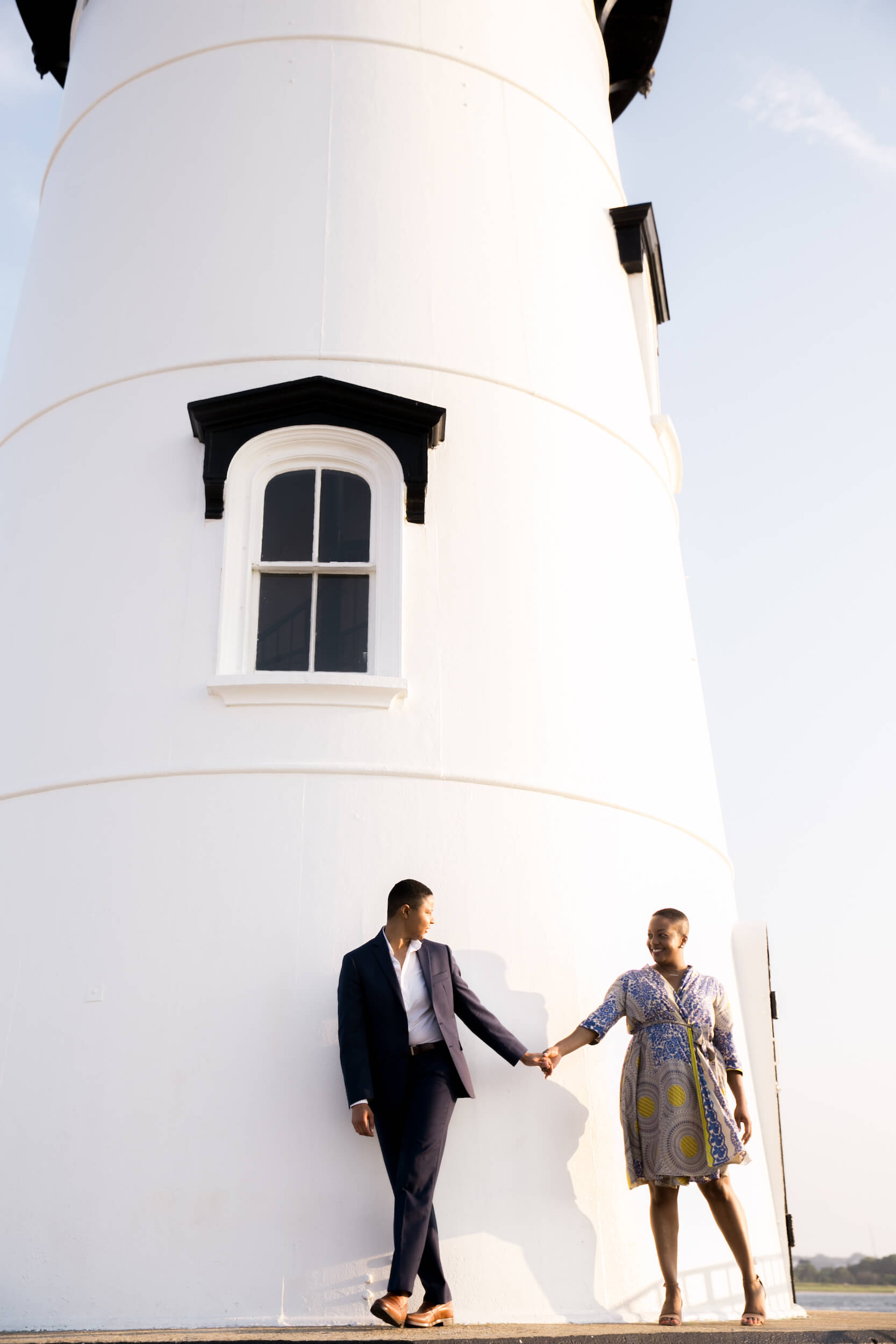 A Lesbian couple hold hands while walking around a lighthouse in Martha's Vineyard, USA.