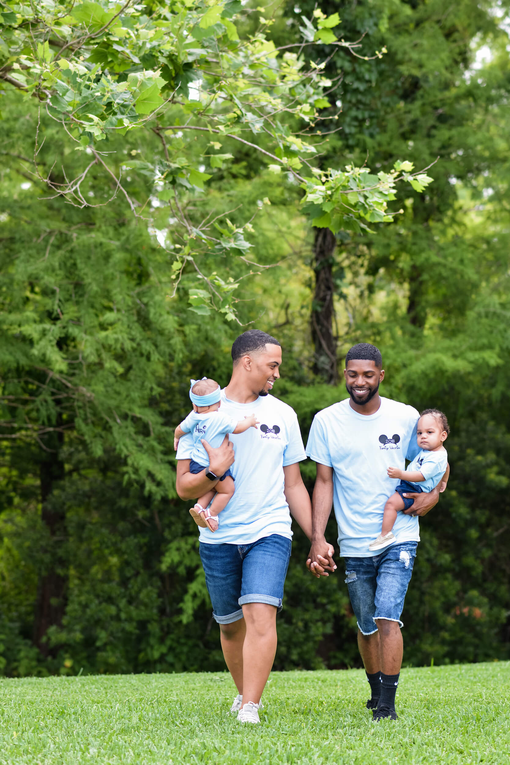 Two dads hold hands and their babies in Orlando, USA.