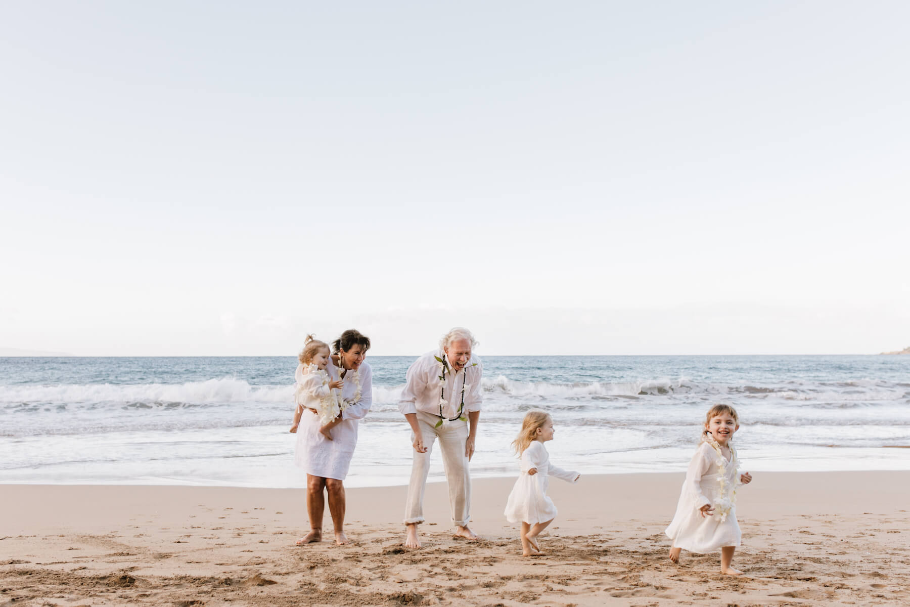 grandparents with their grandkids running on the beach in Maui, Hawaii