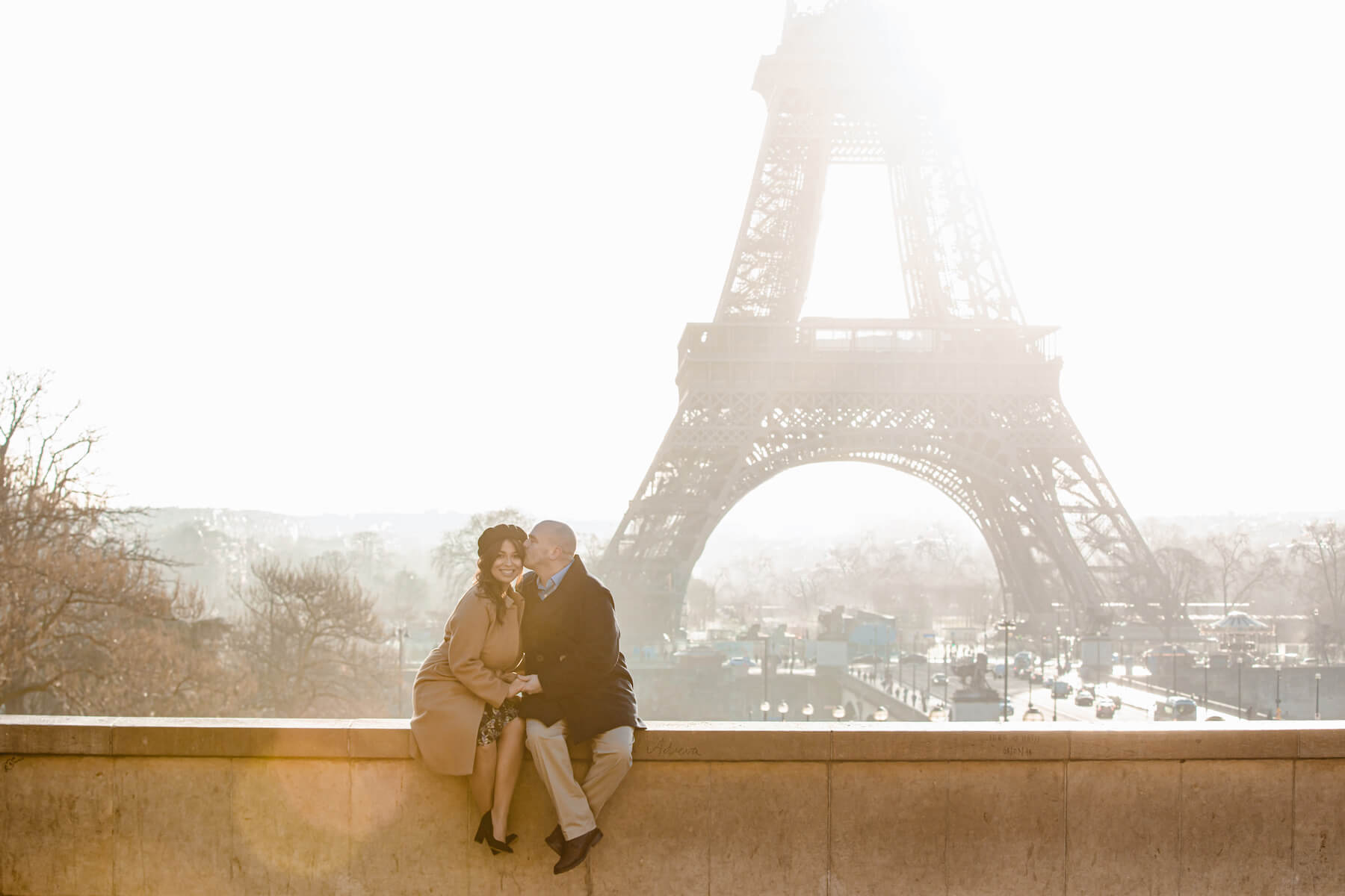 couple sitting on a ledge with the Eiffel tower in the background in Paris, France