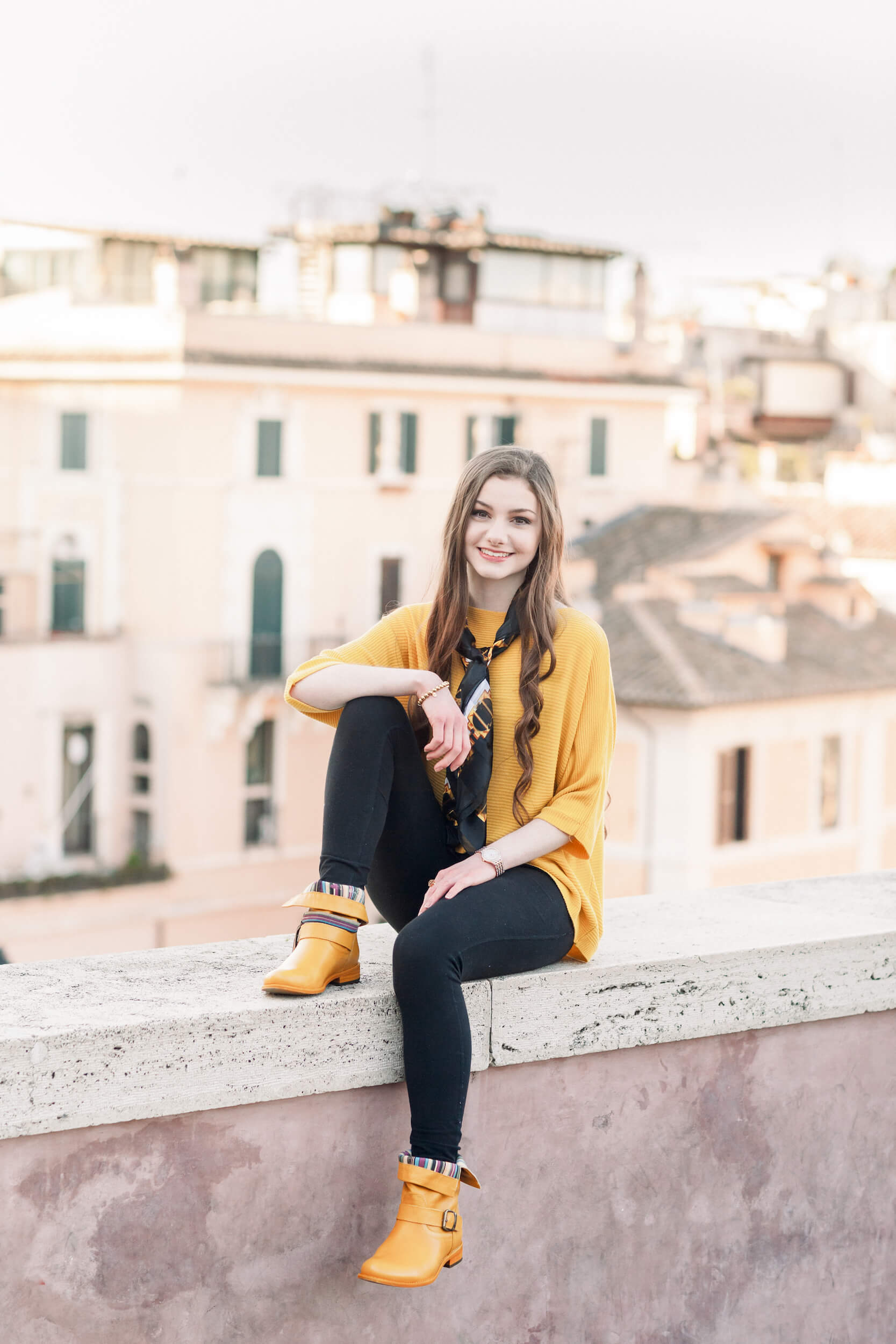 woman sitting on a ledge, with a beautiful courtyard in the background  in Rome, Italy