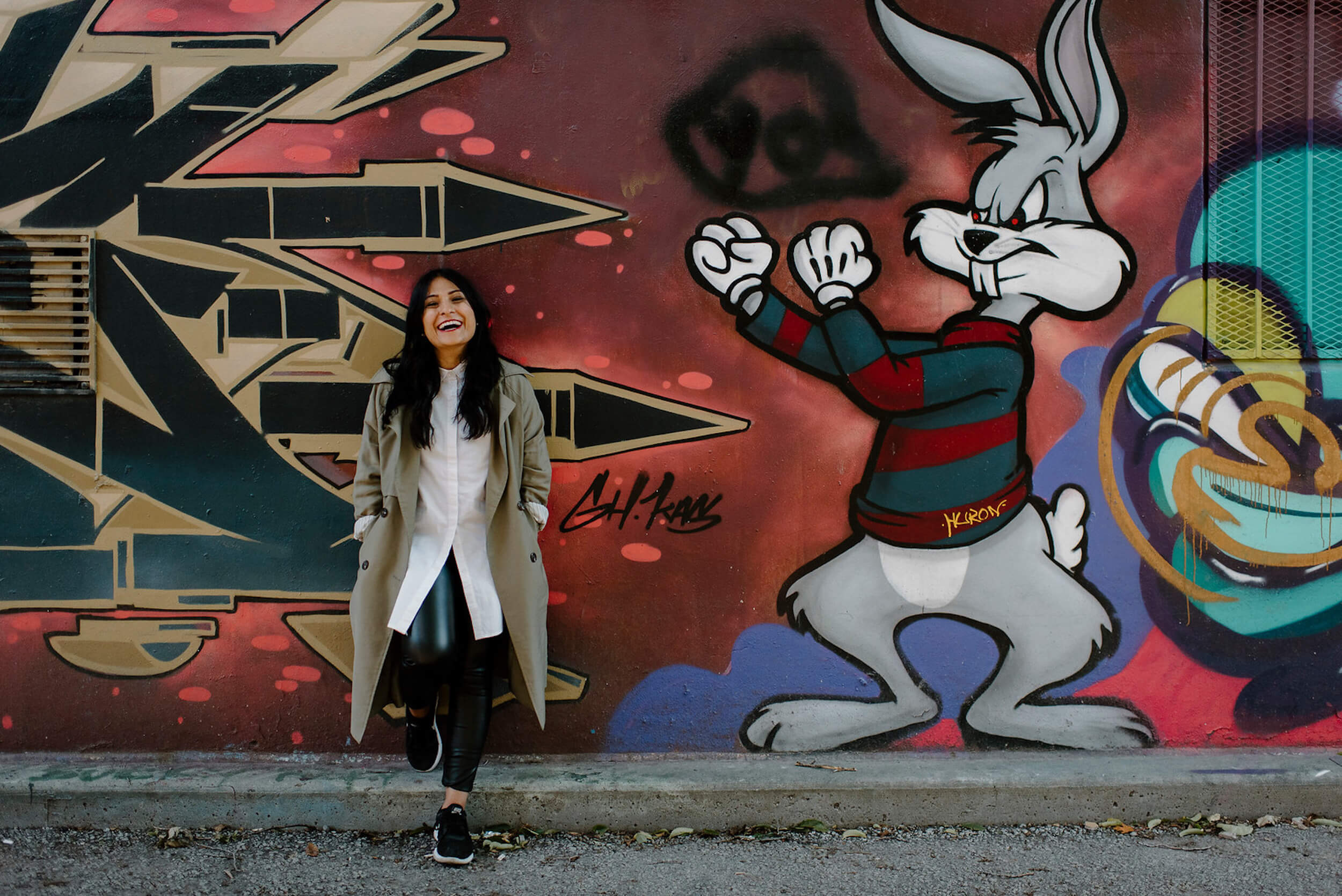 Woman standing in front of a colourful wall laughing in Toronto, Ontario
