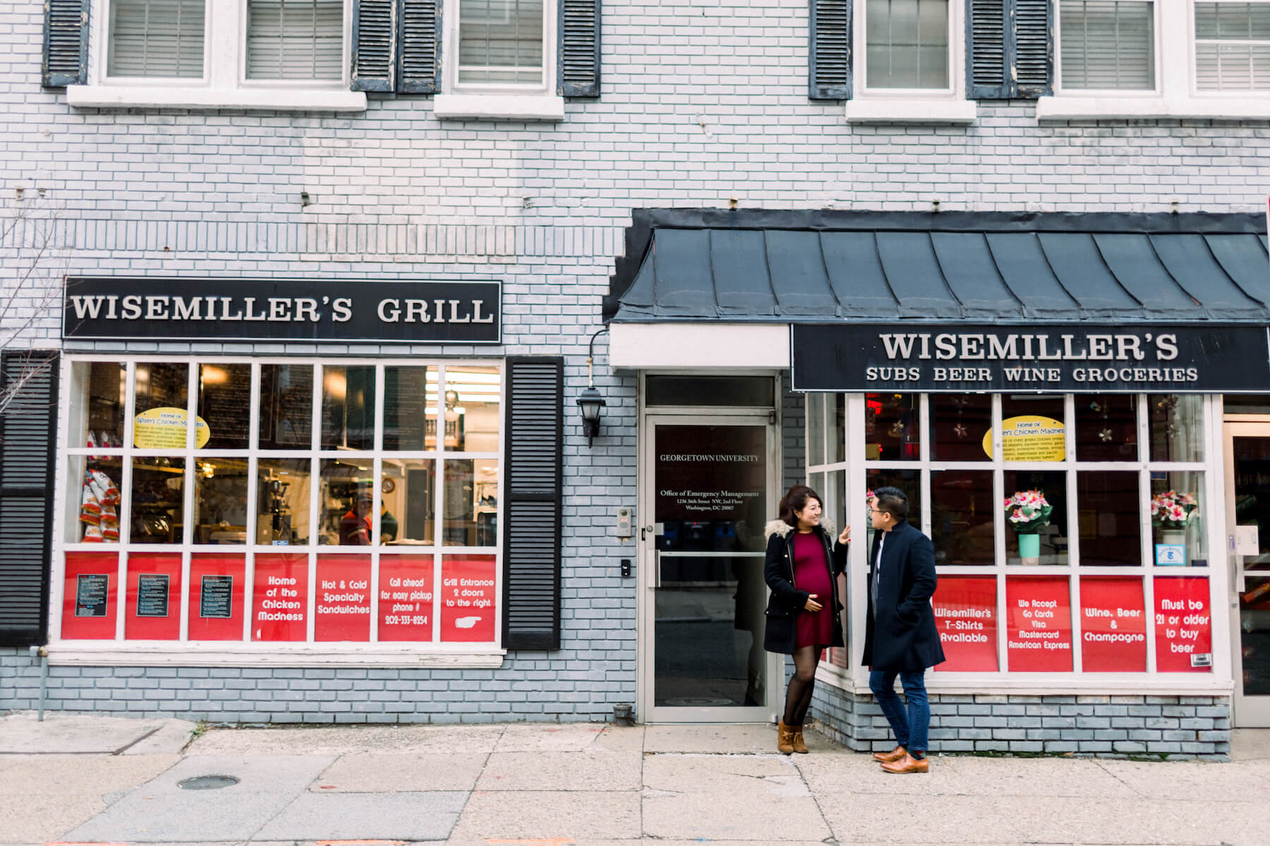 Couple pose in front of the Wisemiller's Grill in Washington DC on a couple photoshoot with Flytographer.