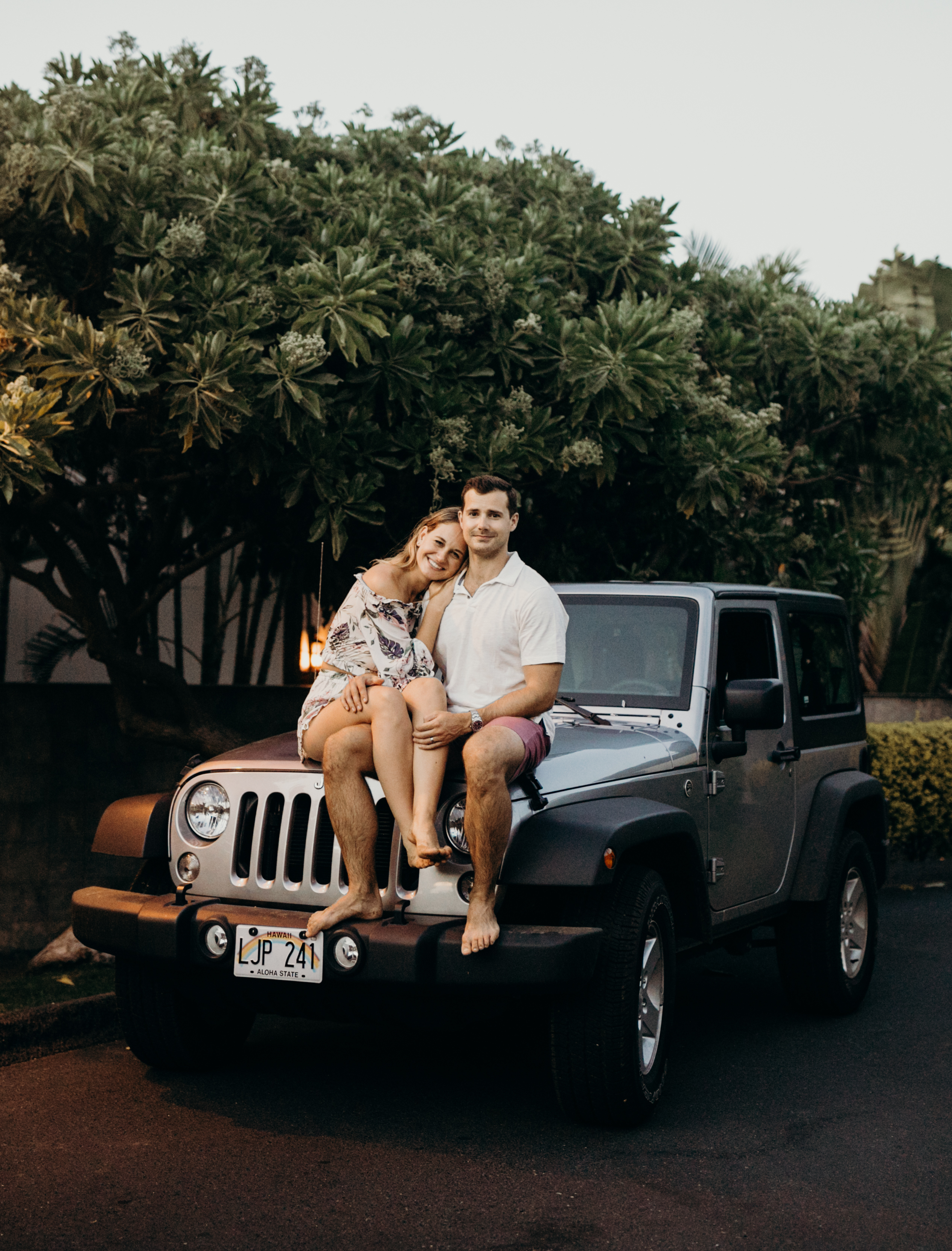 A couple hugging and sitting on a Jeep rental car in Maui, Hawaii on a couple photoshoot with Flytographer.
