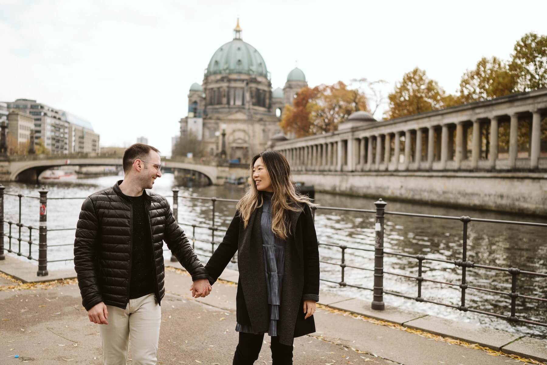 A couple holds hands looking at each other on a sunny say next to a canal in Berlin.