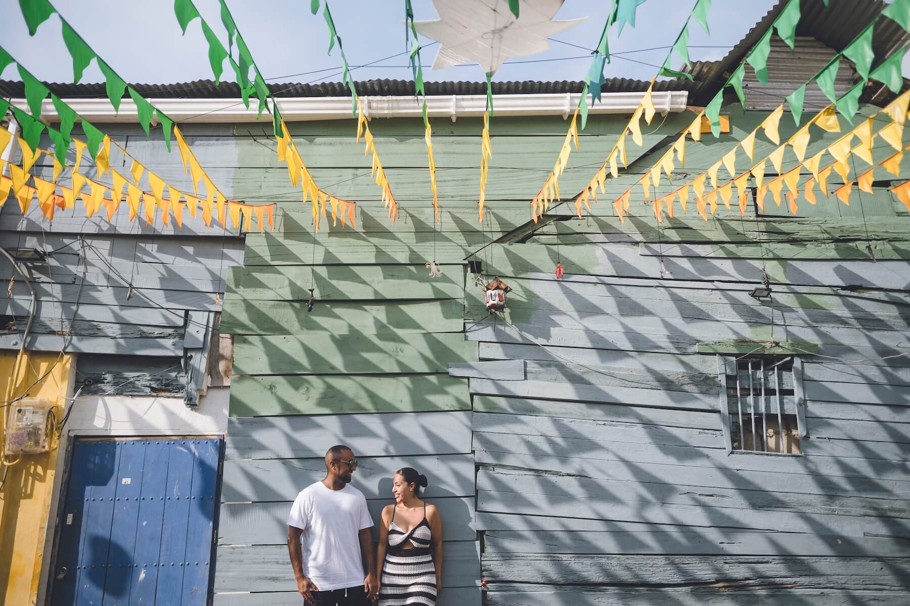A couple looks at each other and leans against a blue building in Cartagena.