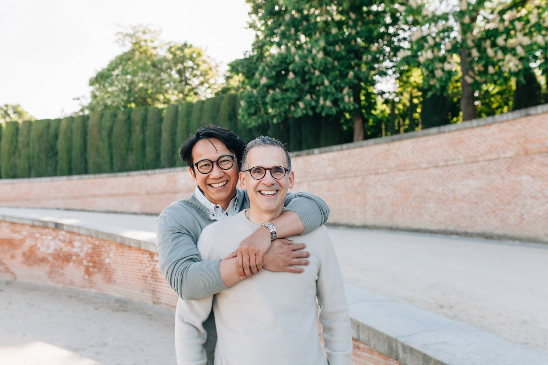 A man wraps his arms around his partner while they smile in Madrid.