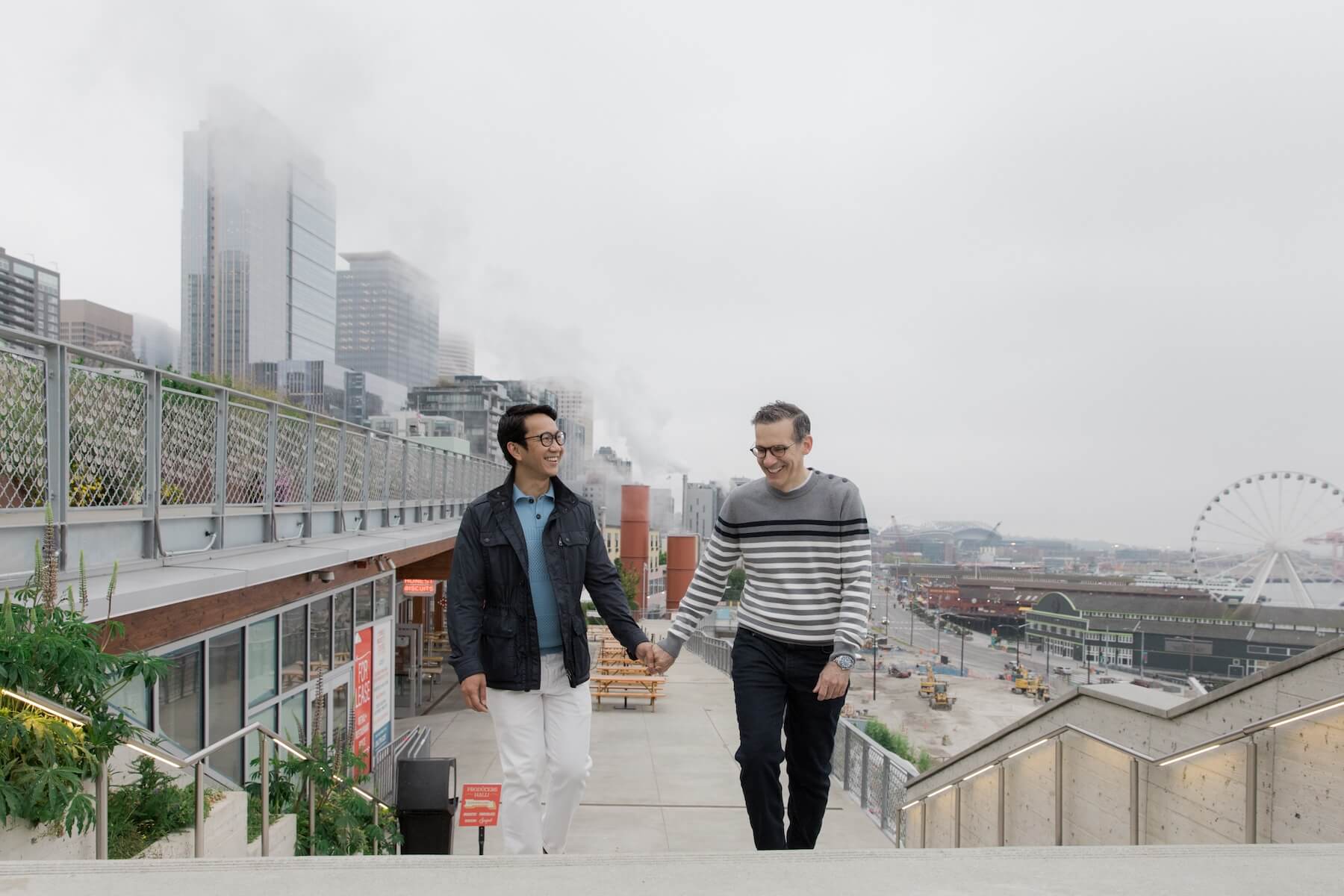 Two men hold hands while walking up stairs outside in Seattle, USA.