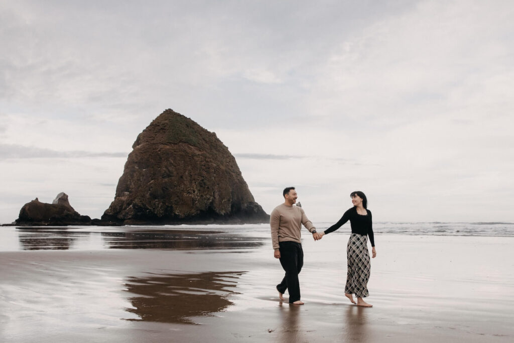 A couple walking on the beach in Cannon Beach on a couples photoshoot with Flytographer.